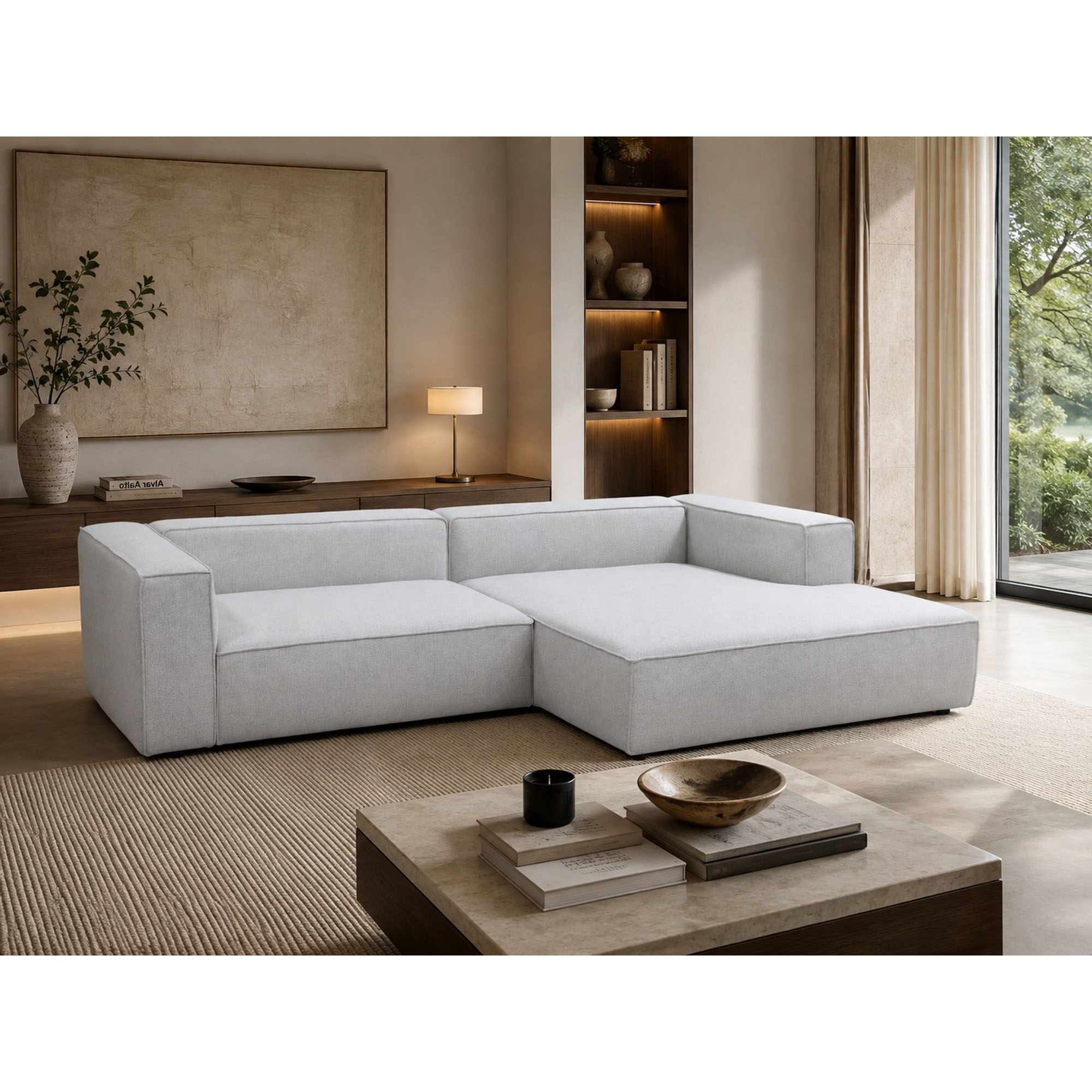 Großzügiges Ecksofa in Weiß mit rechter Liegefläche, dargestellt in einem wohnlichen Ambiente mit Teppich und Couchtisch. Die Ausführung kommt ohne lose Rückenkissen aus.