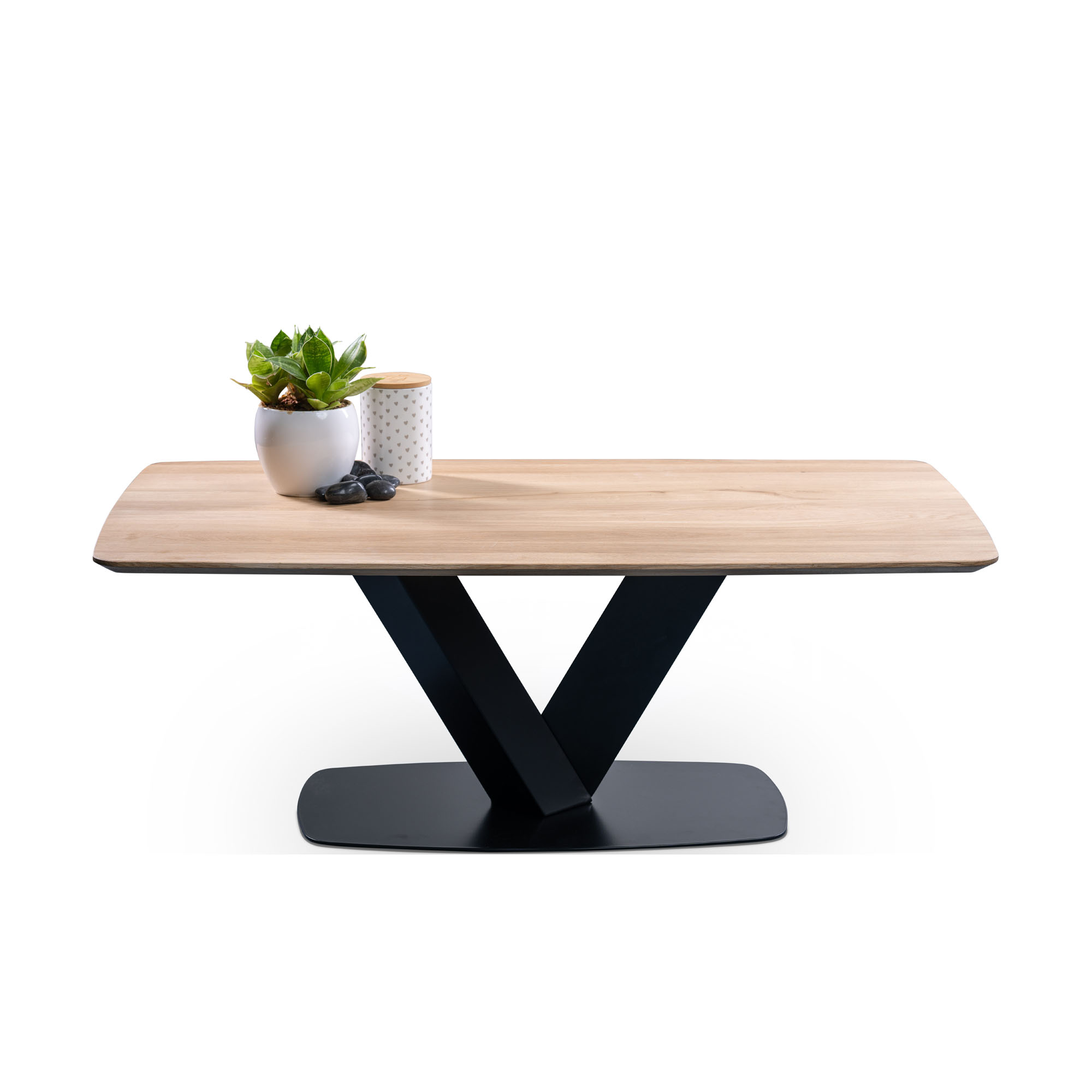 Rechteckiger Tisch mit heller Holzplatte und V-förmigem schwarzen Metallgestell, darauf ein Blumentopf, ein Deko-Behälter und zwei Steine