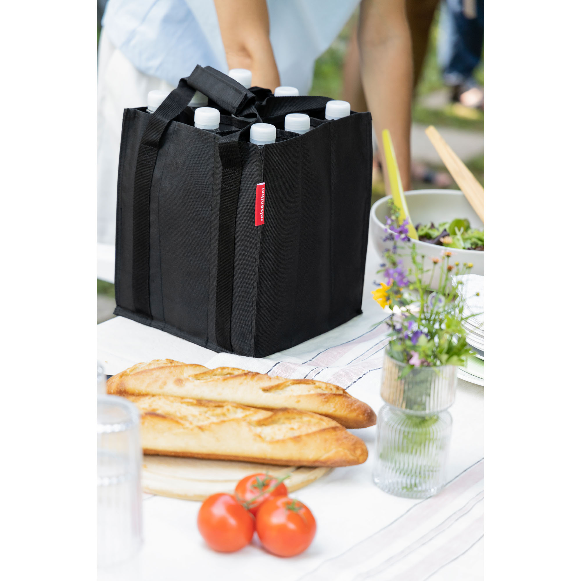 Flaschentasche von Reisenthel, Modell Bottlebag, in Schwarz, mit Flaschen auf einem gedeckten Tisch im Freien.
