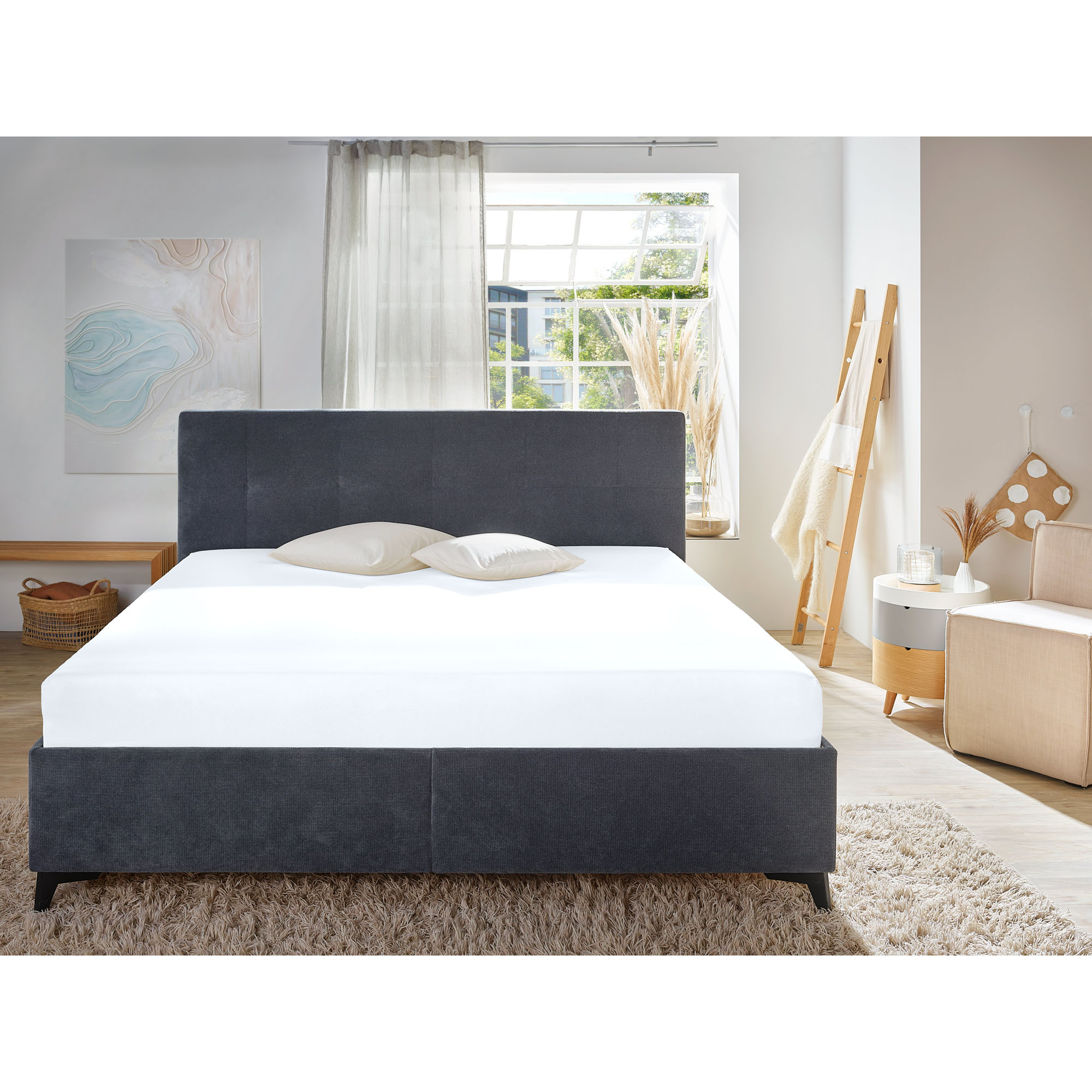 Spannbetttuch in Weiß auf einem Bett in einem hellen Schlafzimmer; weiße Bettwäsche und ein dunkles Kopfteil sind sichtbar; Größe 100 x 200 x 30 cm.