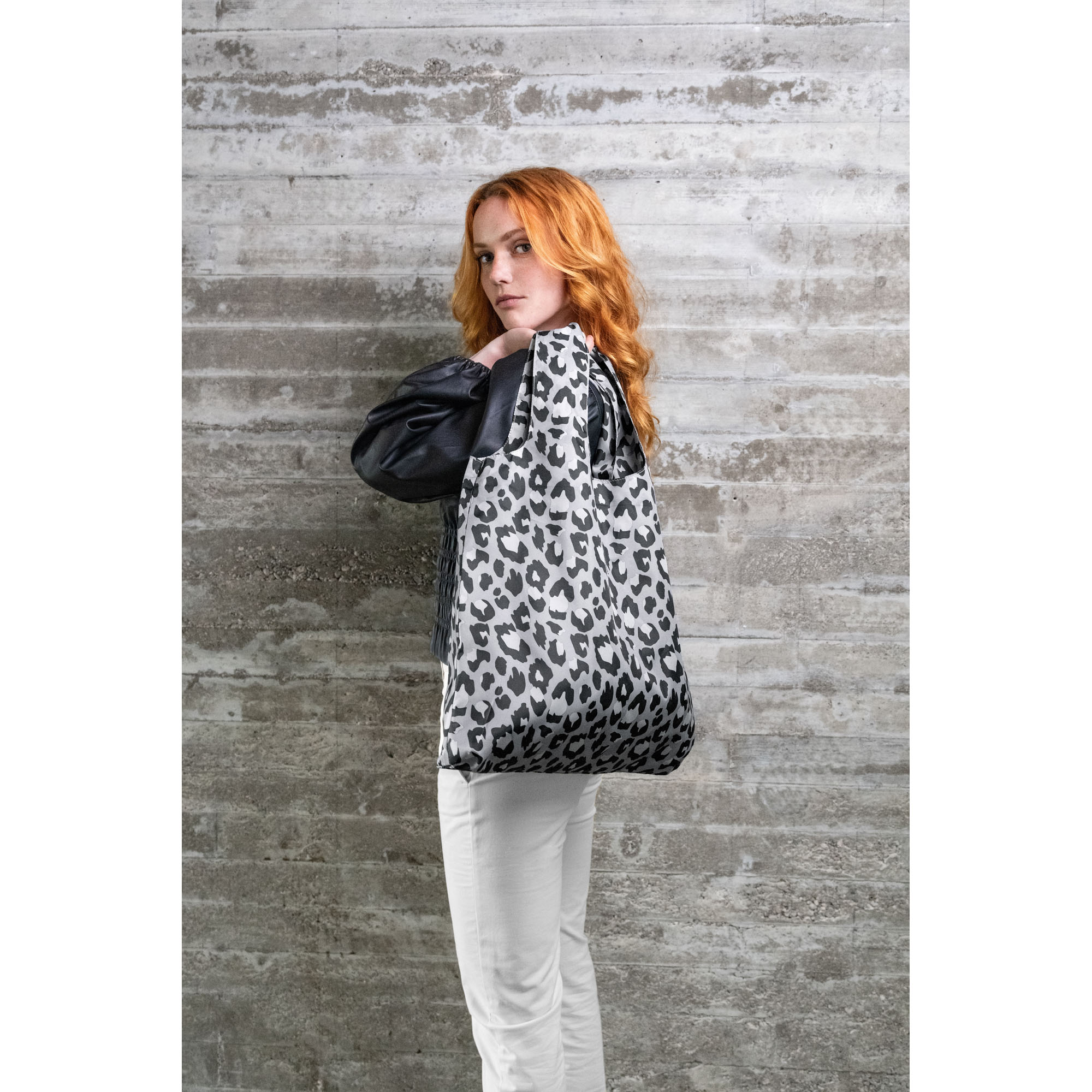 Faltbare Einkaufstasche von Reisenthel, Modell Mini Maxi Shopper, in Schwarz und Weiß mit Leopardenmuster, von einer Person über der Schulter getragen.