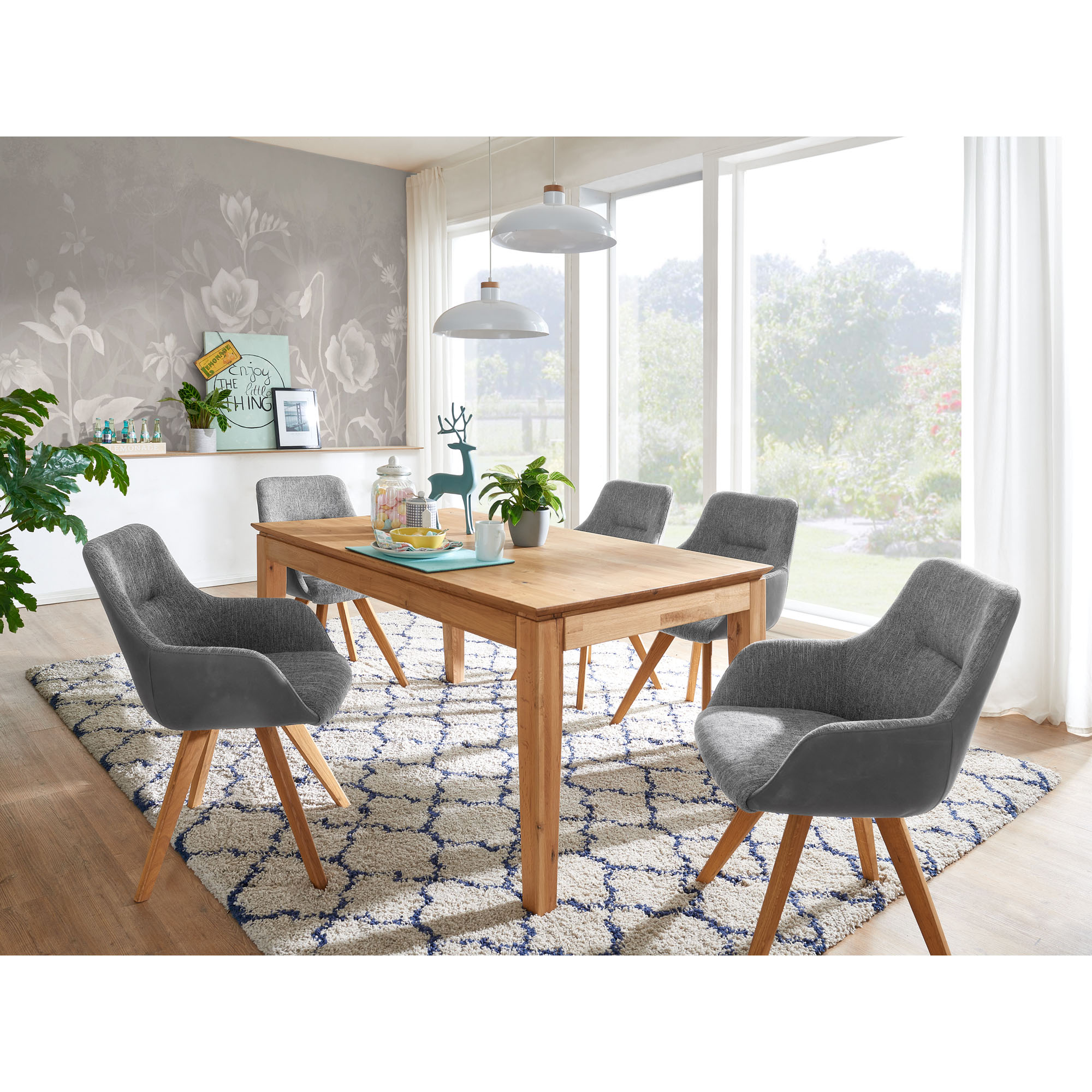 Rechteckiger Esstisch aus Holz mit mehreren Stühlen in einem hellen Esszimmer mit Teppich und Fenstern