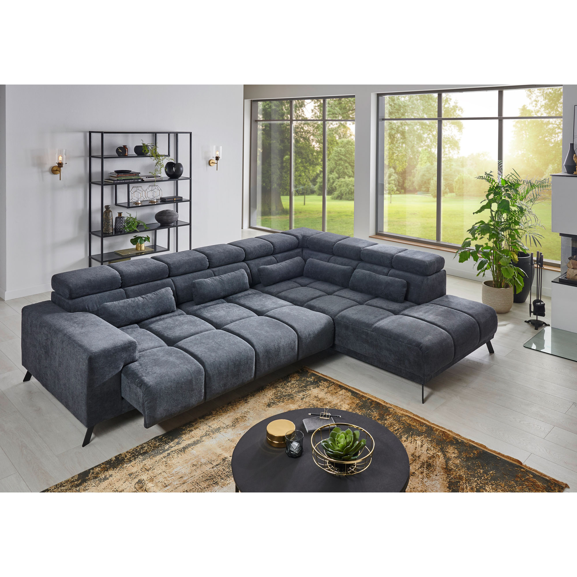 Ecksofa in dunkelgrauer Polsterung aus seitlicher Perspektive mit Blick auf Regal, große Fenster und Couchtisch
