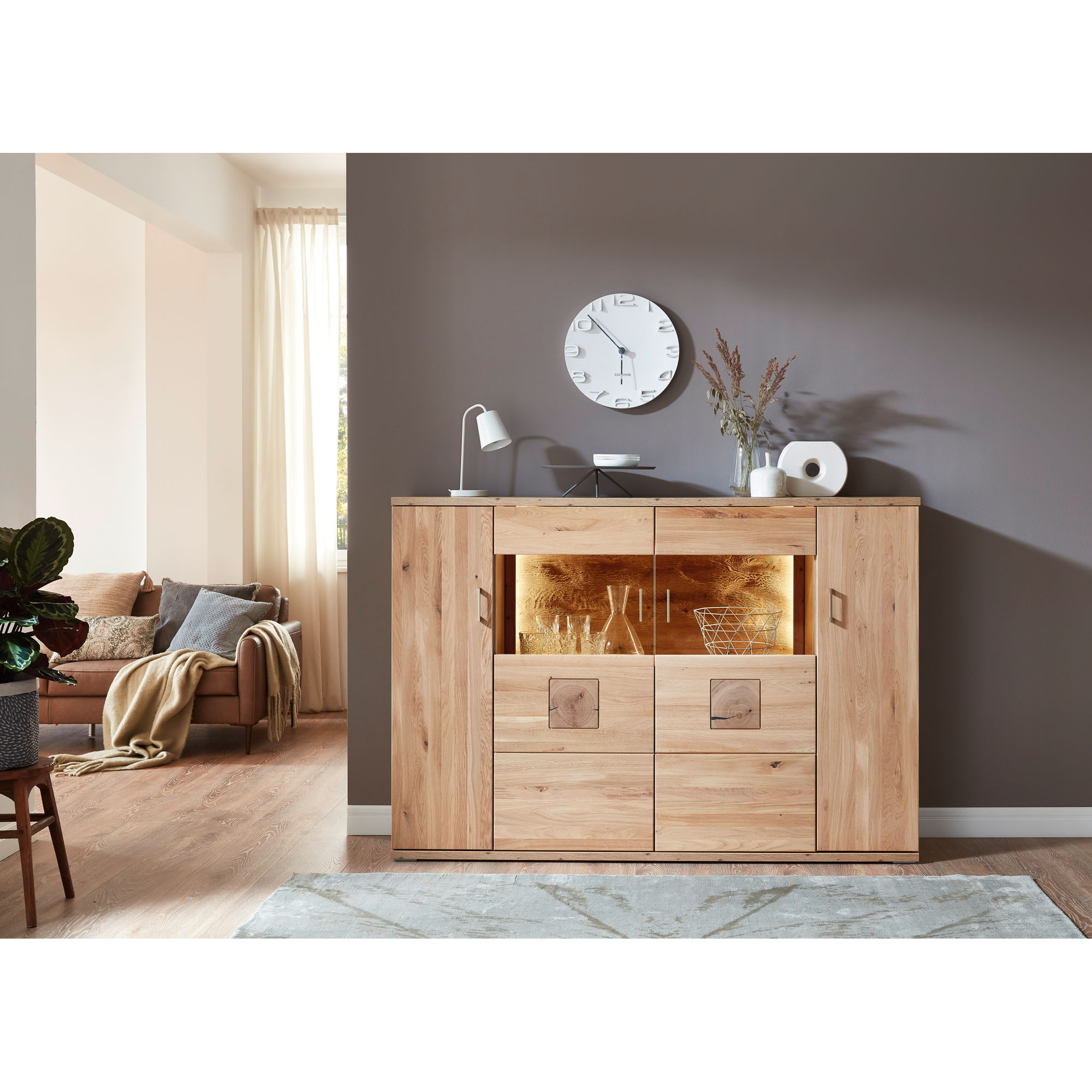 Highboard in natürlicher Holzoptik mit Dekoration vor einer hellen Wand in einem modern eingerichteten Wohnraum