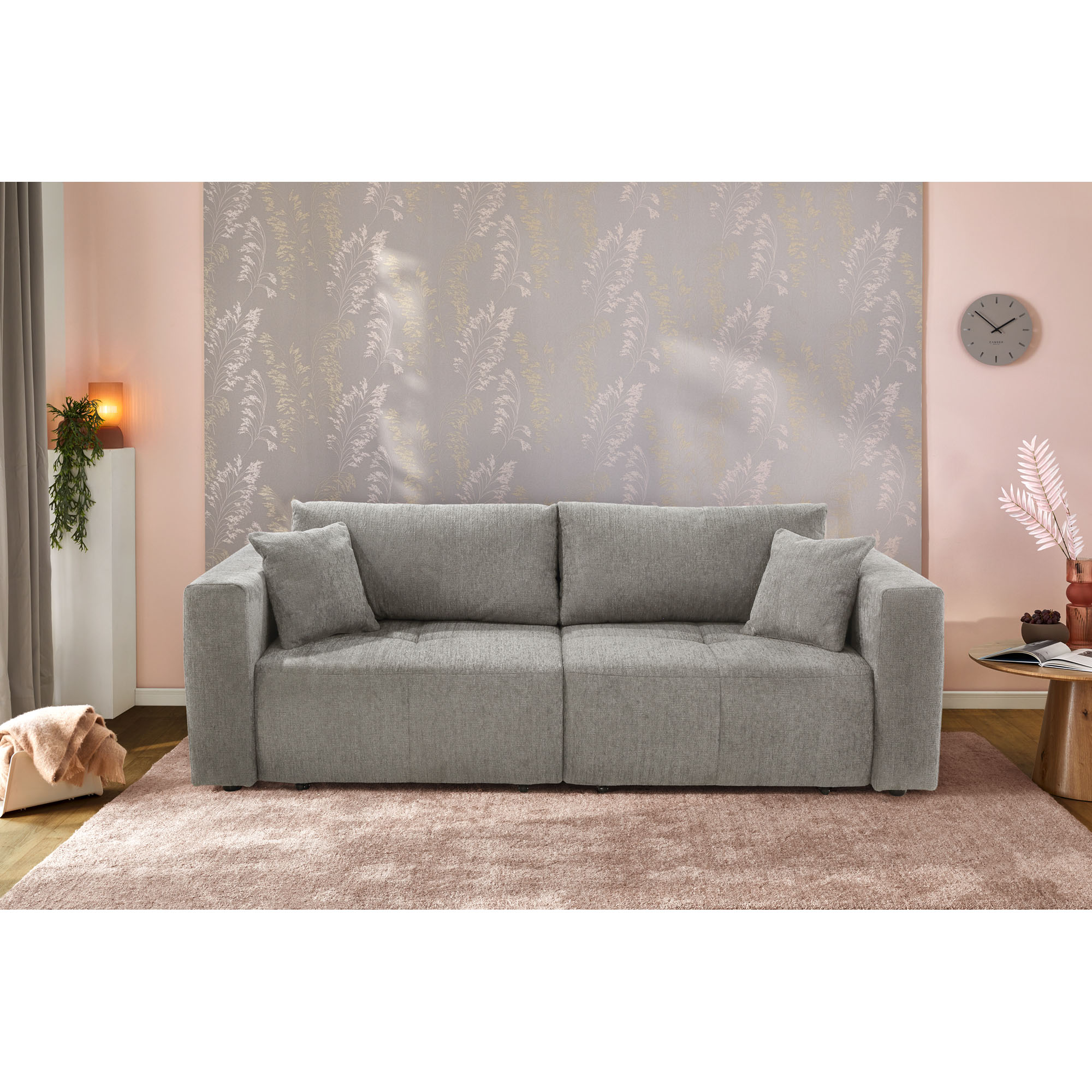 Graues Schlafsofa mit zwei Kissen in modern eingerichtetem Wohnzimmer mit rosa Teppich und gemusterter Wand
