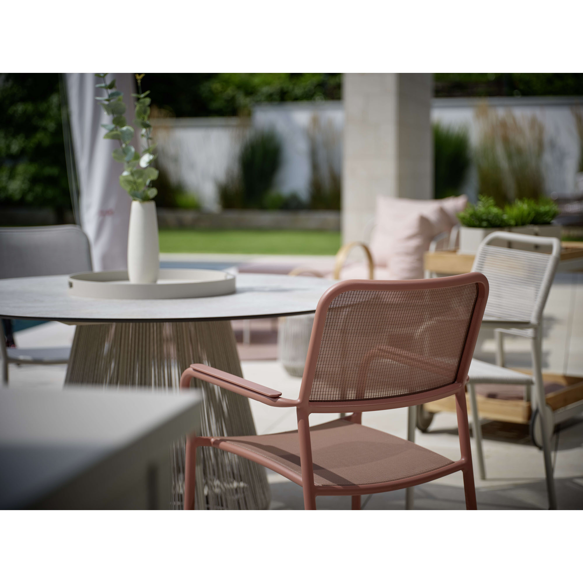 Gartenstuhl mit Armlehnen an einem Tisch im überdachten Außenbereich
