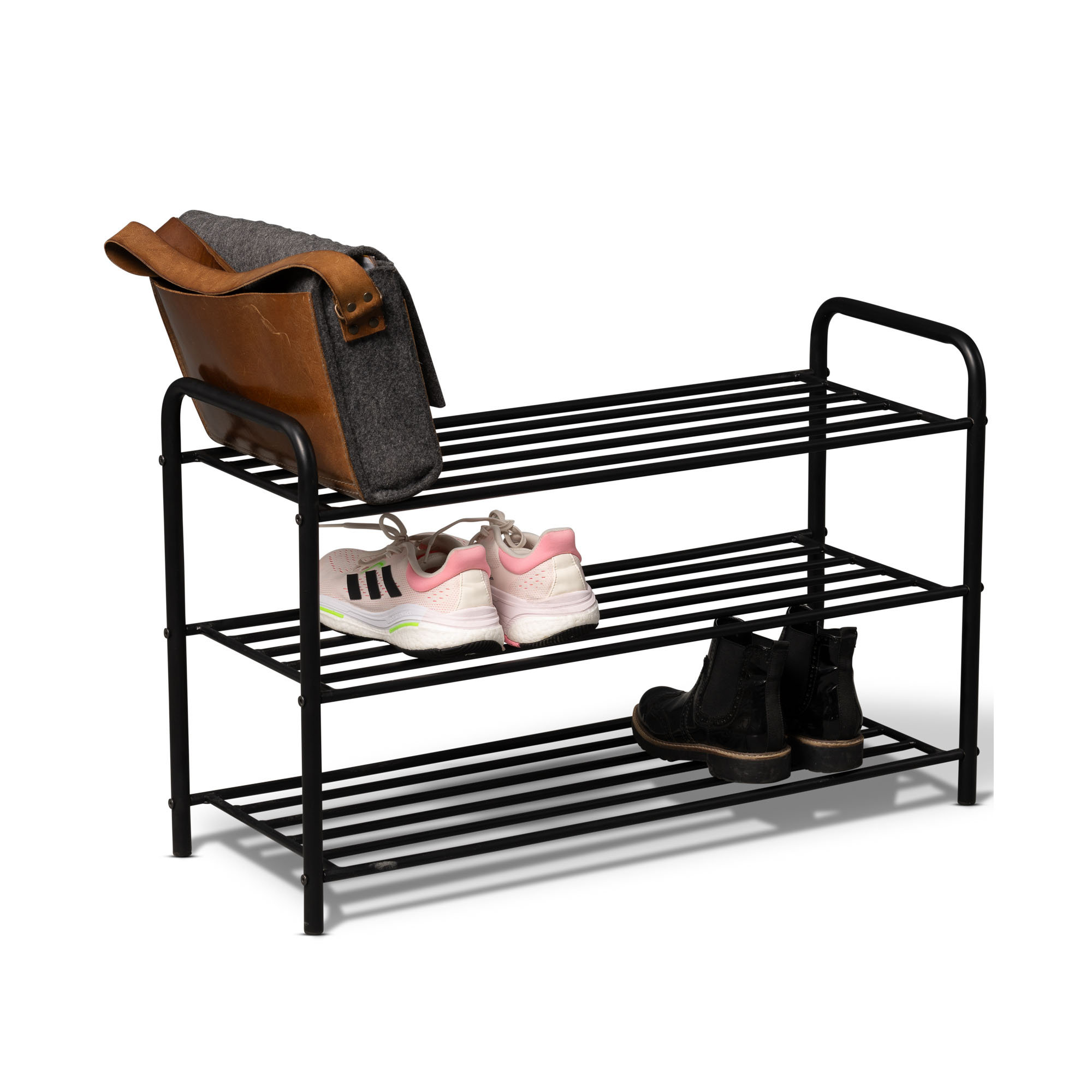 Schwarzes dreistufiges Metallregal mit einer braunen Tasche auf der oberen Ablage, weißen Sportschuhen auf der mittleren Ebene und schwarzen Stiefeletten auf der unteren Ebene vor weißem Hintergrund