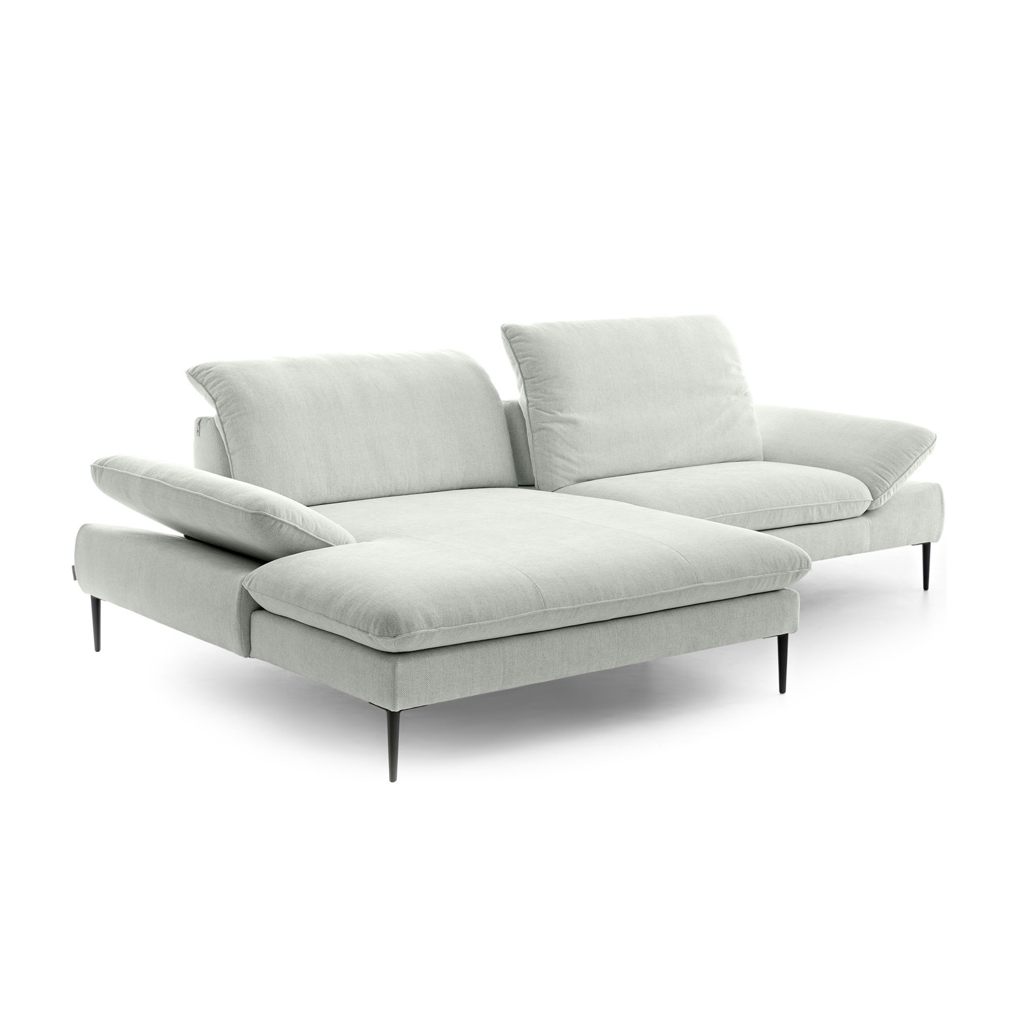 Freigestellte Polstergarnitur in Light Grey mit Ottomane auf der linken Seite, mehreren Rückenkissen und unterschiedlich ausgerichteten Rückenlehnen