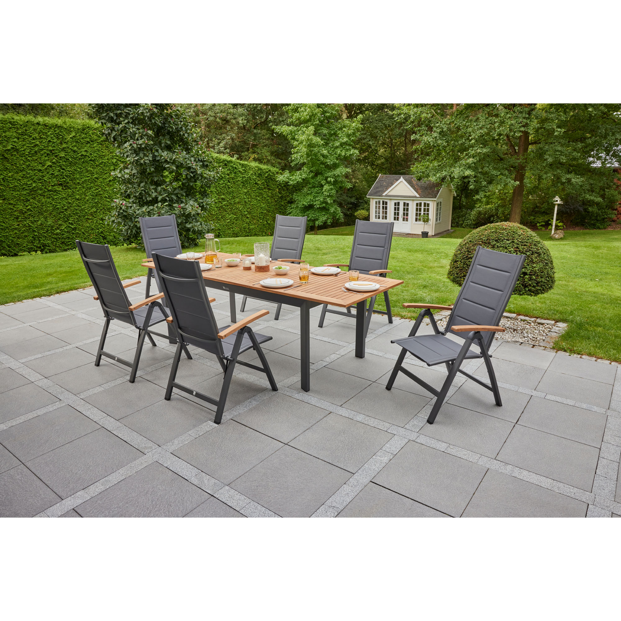 Rechteckiger Gartentisch mit mehreren Gartenstühlen auf einer Terrasse im Garten