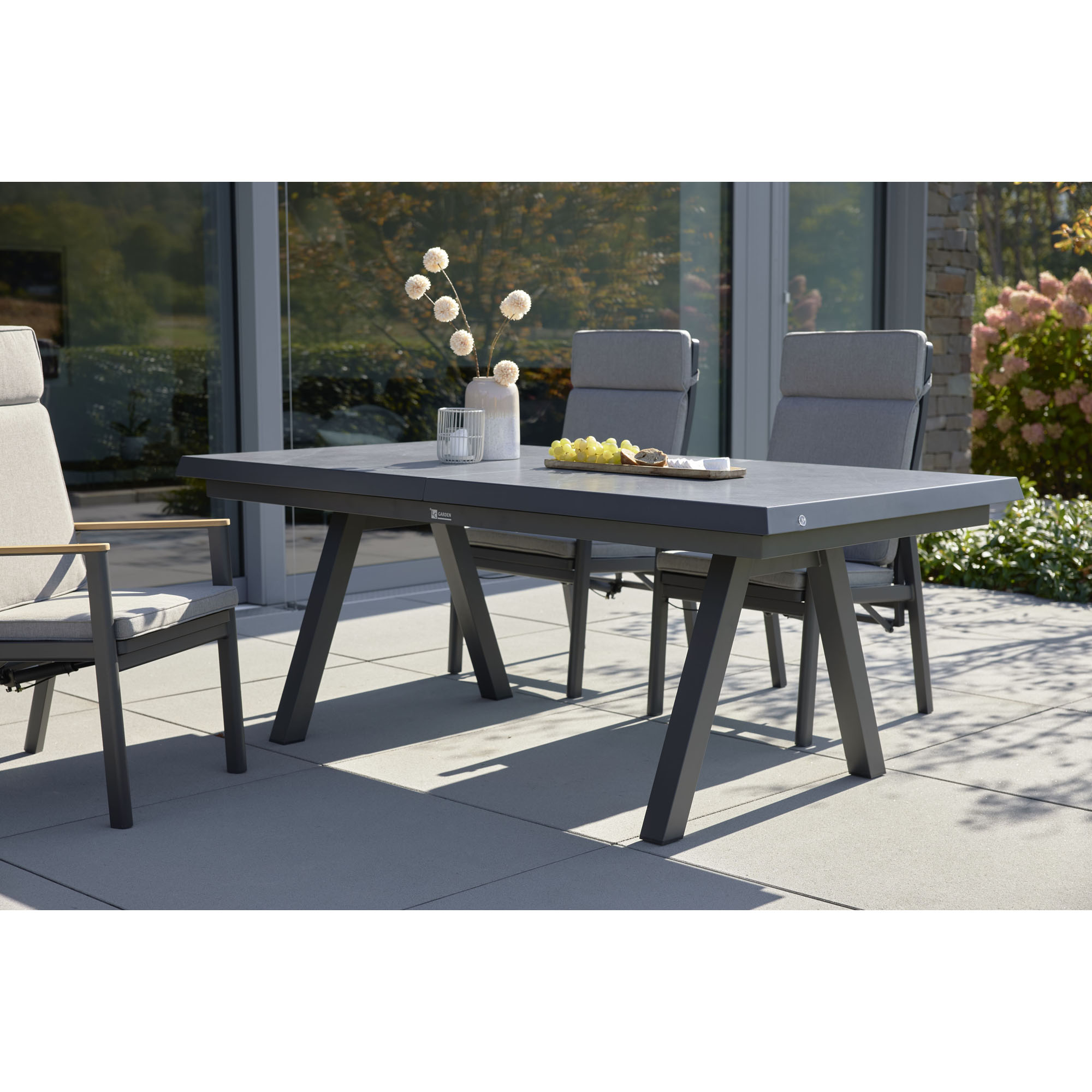 Gartentisch mit gepolsterten Gartenstühlen auf einer Terrasse vor einem Wohnhaus