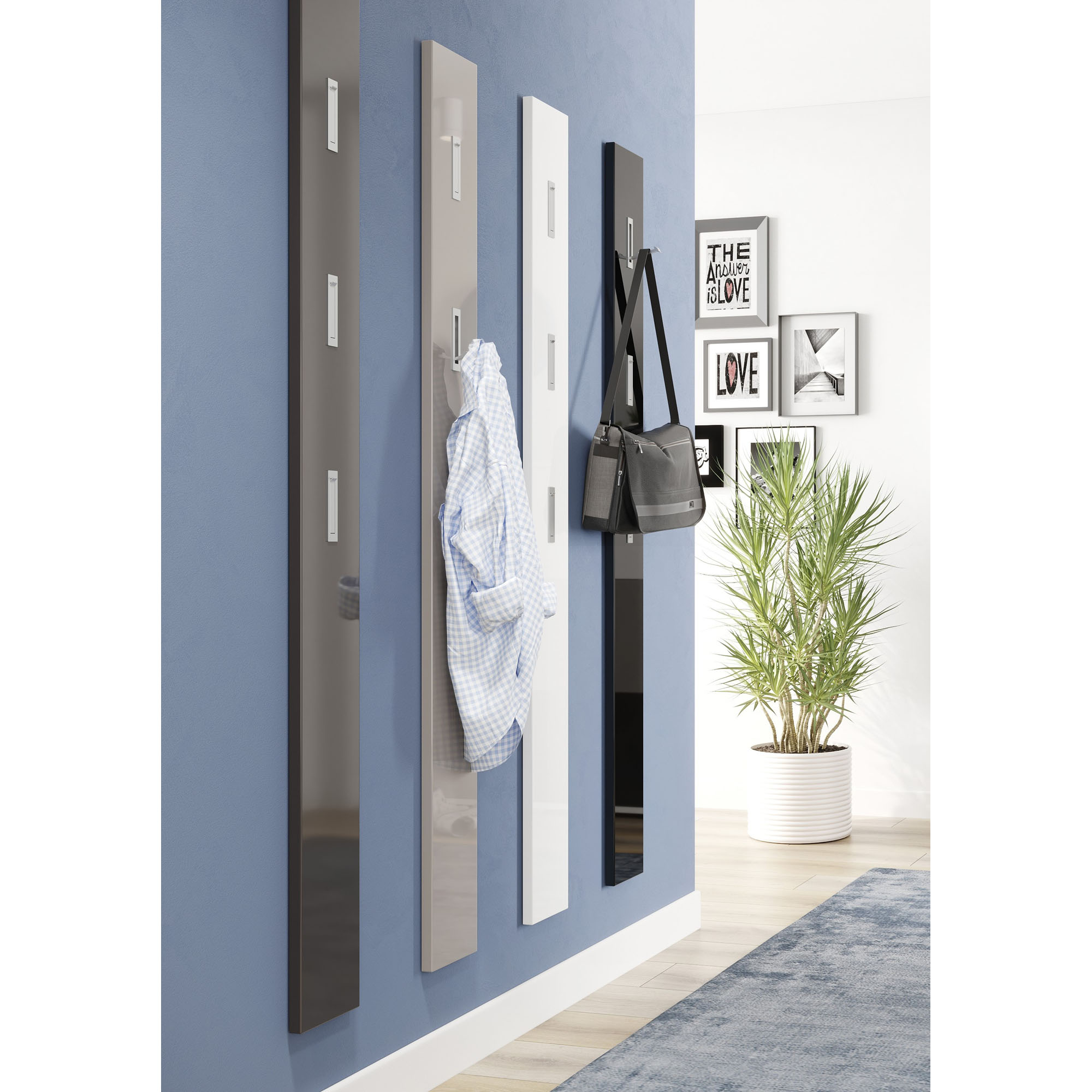 Mehrere schmale Wandpaneele mit Haken in unterschiedlichen Farben an einer blauen Wand mit Kleidung und Taschen