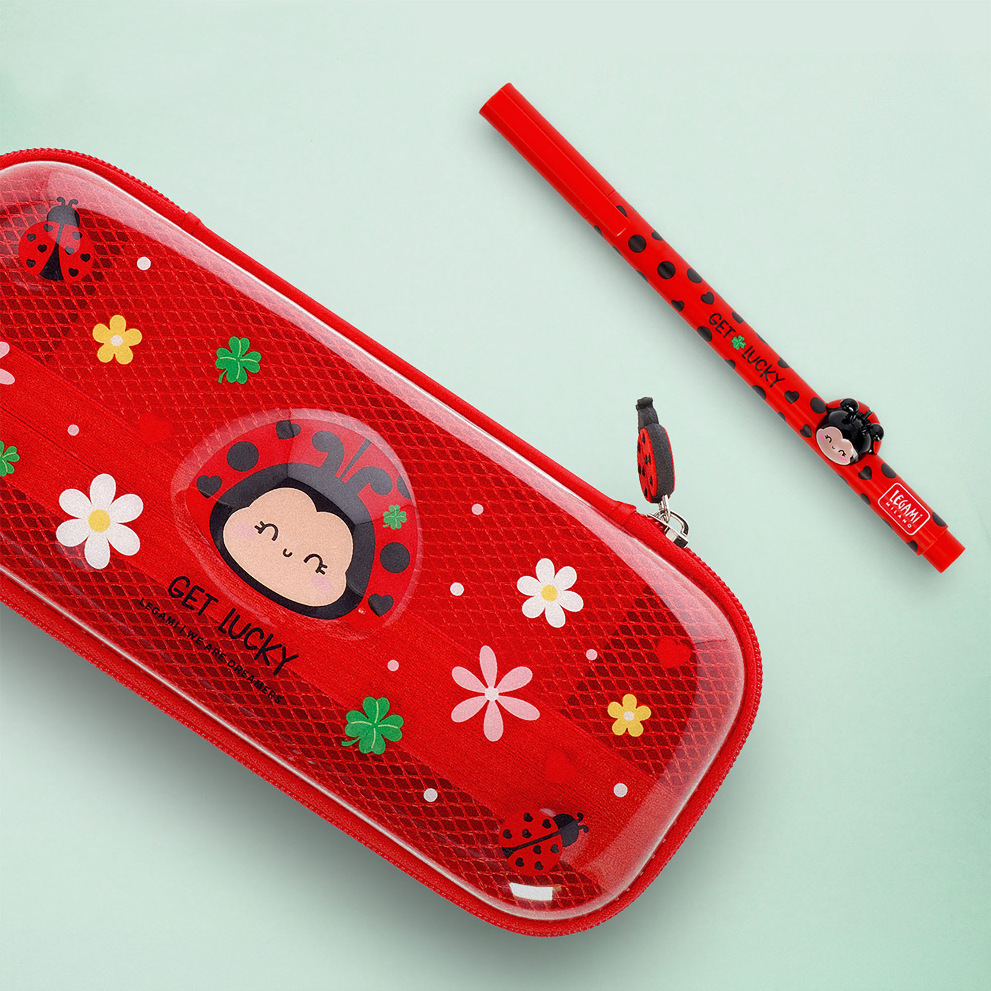 Rotes Federmäppchen im Marienkäfer-Design, geschlossen neben einem roten Stift und kleinen Schreibutensilien dargestellt.