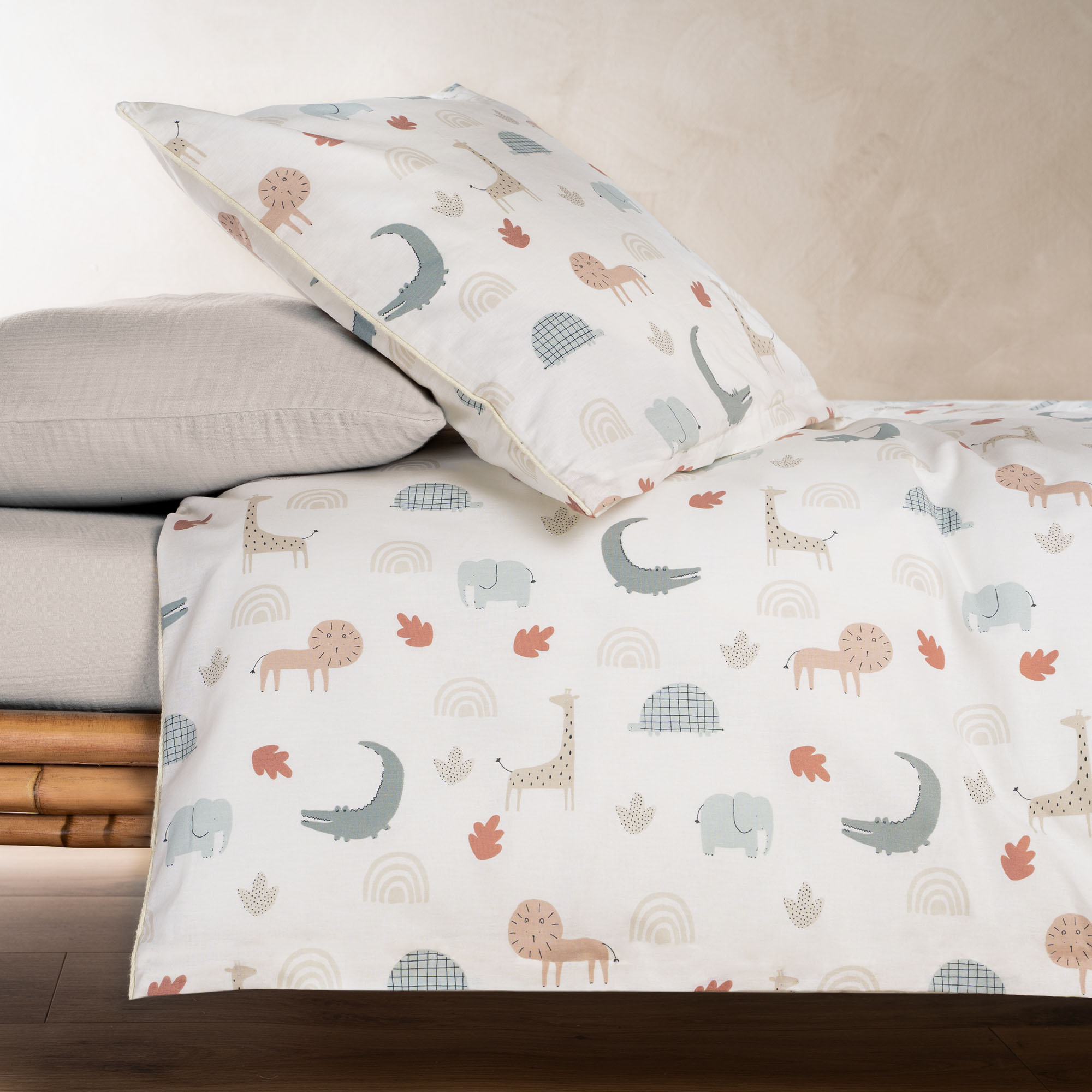 Die Kinderbettwäsche mit Tiermotiven liegt auf einem Kinderbett, das Kissen ist leicht aufgestellt