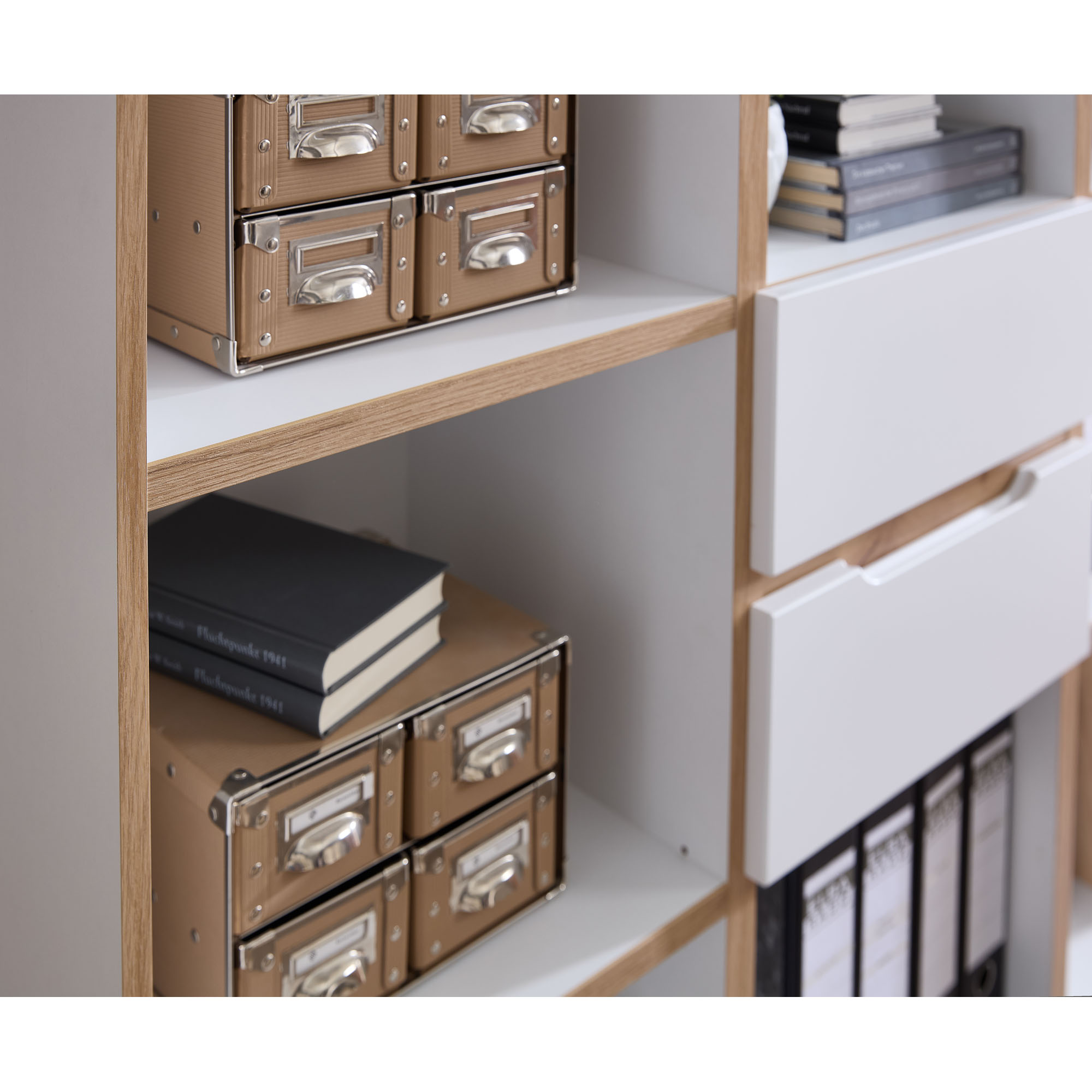 Nahaufnahme eines weißen Regalfachs mit kleinen Aufbewahrungsboxen und mehreren gestapelten Büchern