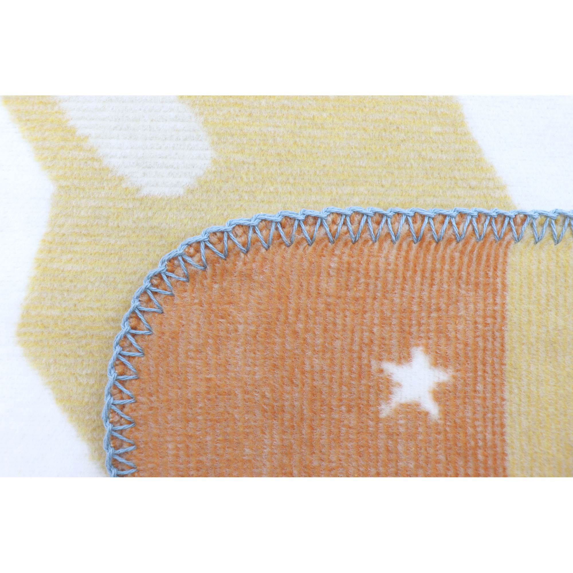 Detail der Babydecke Orbit mit weißem Stern auf orangefarbenem Feld und blau umkettelter Kante.