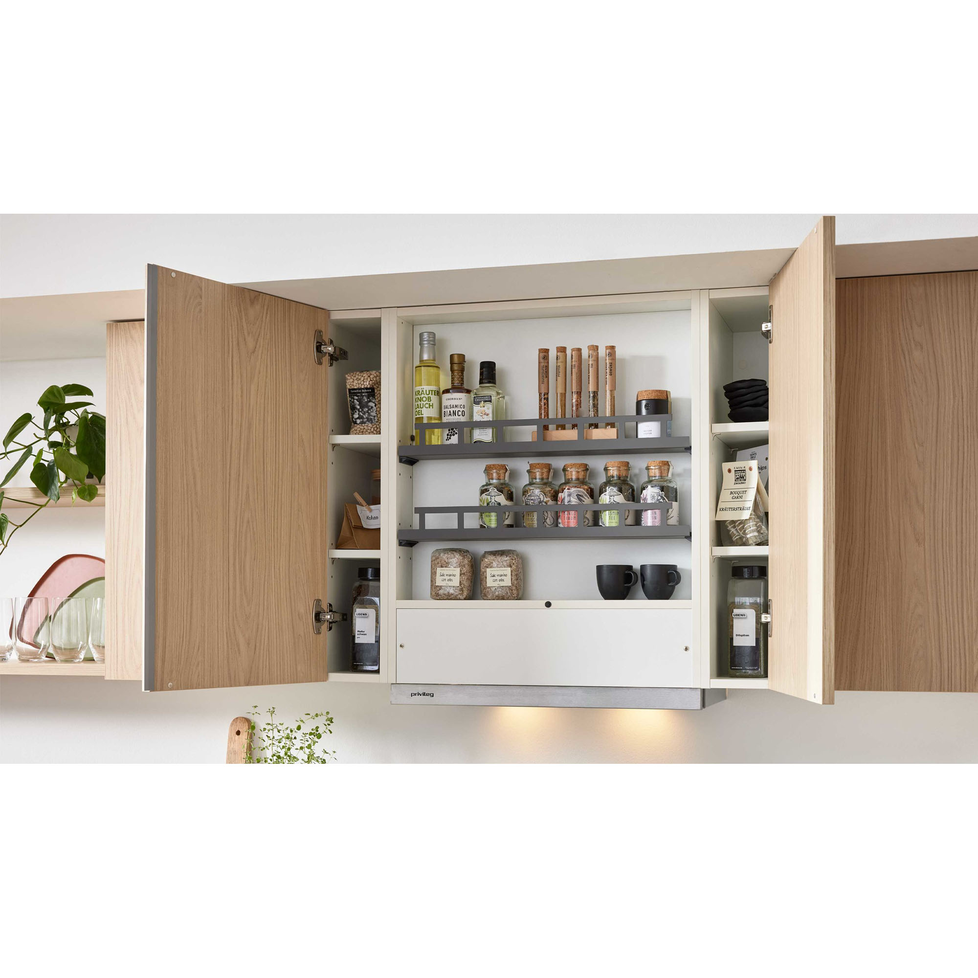 Geöffneter Oberschrank in heller Küche mit Gläsern, Gewürzen und Ölflaschen auf mehreren Regalen