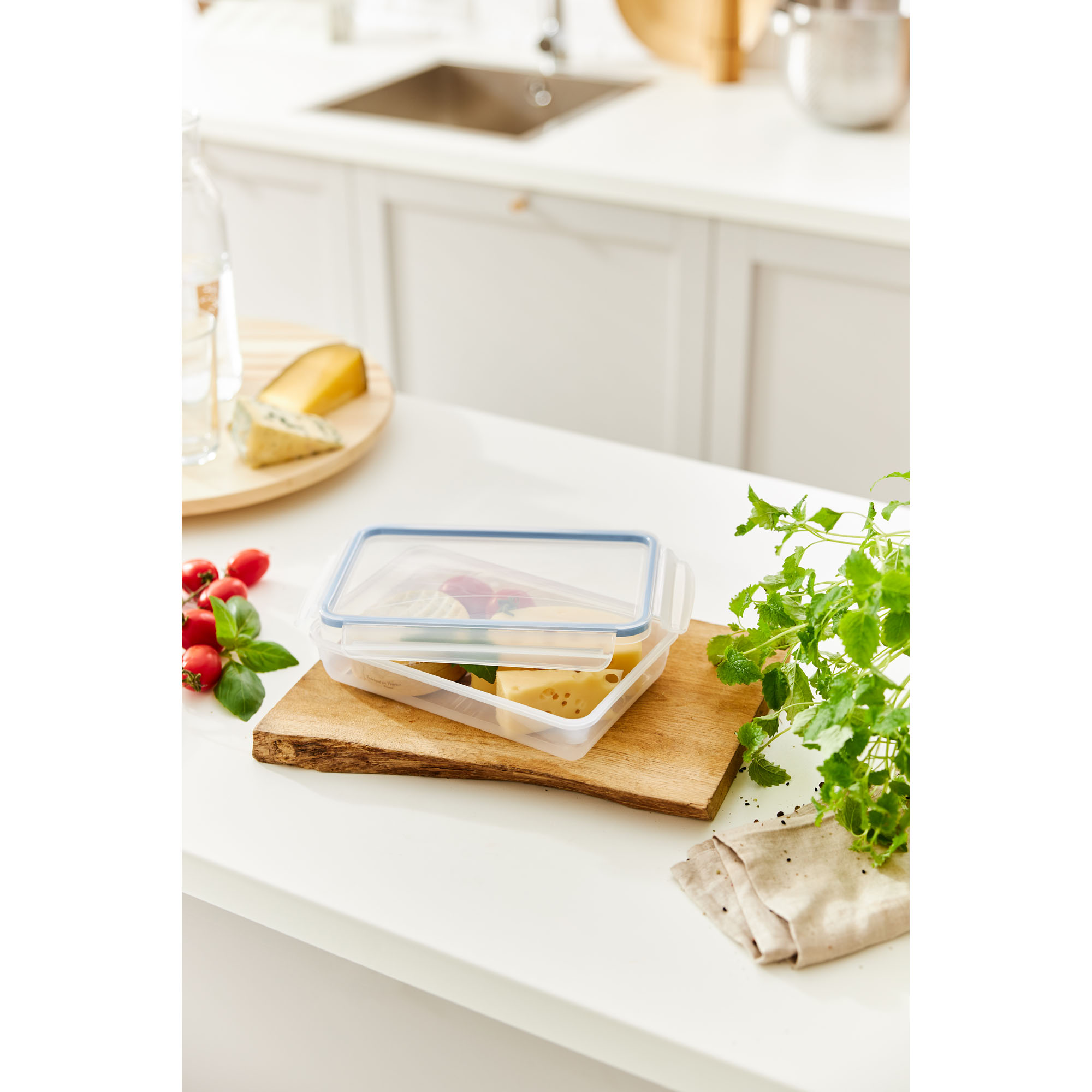 Flache transparente Frischhaltedose mit Lebensmitteln auf einem Holztablett in einer Küche