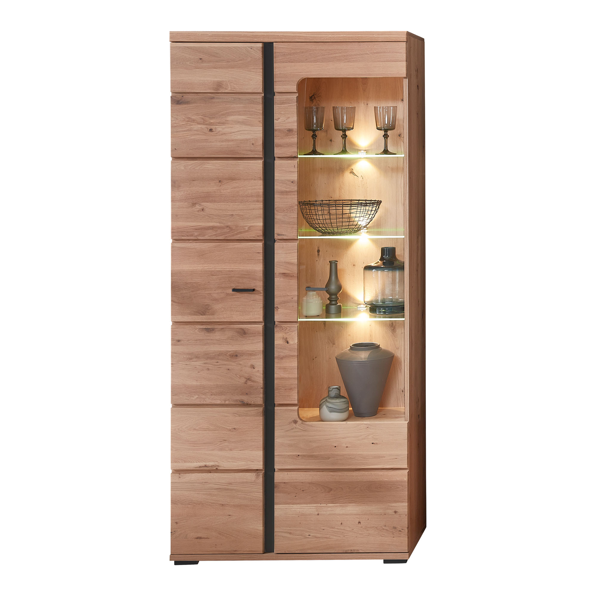 Frontansicht einer Vitrine in Holzoptik. Rechts befindet sich ein offener Bereich mit beleuchteten Glasböden, auf denen Gläser, eine Schale und Dekorationsobjekte stehen. Links sind geschlossene Türen sichtbar.