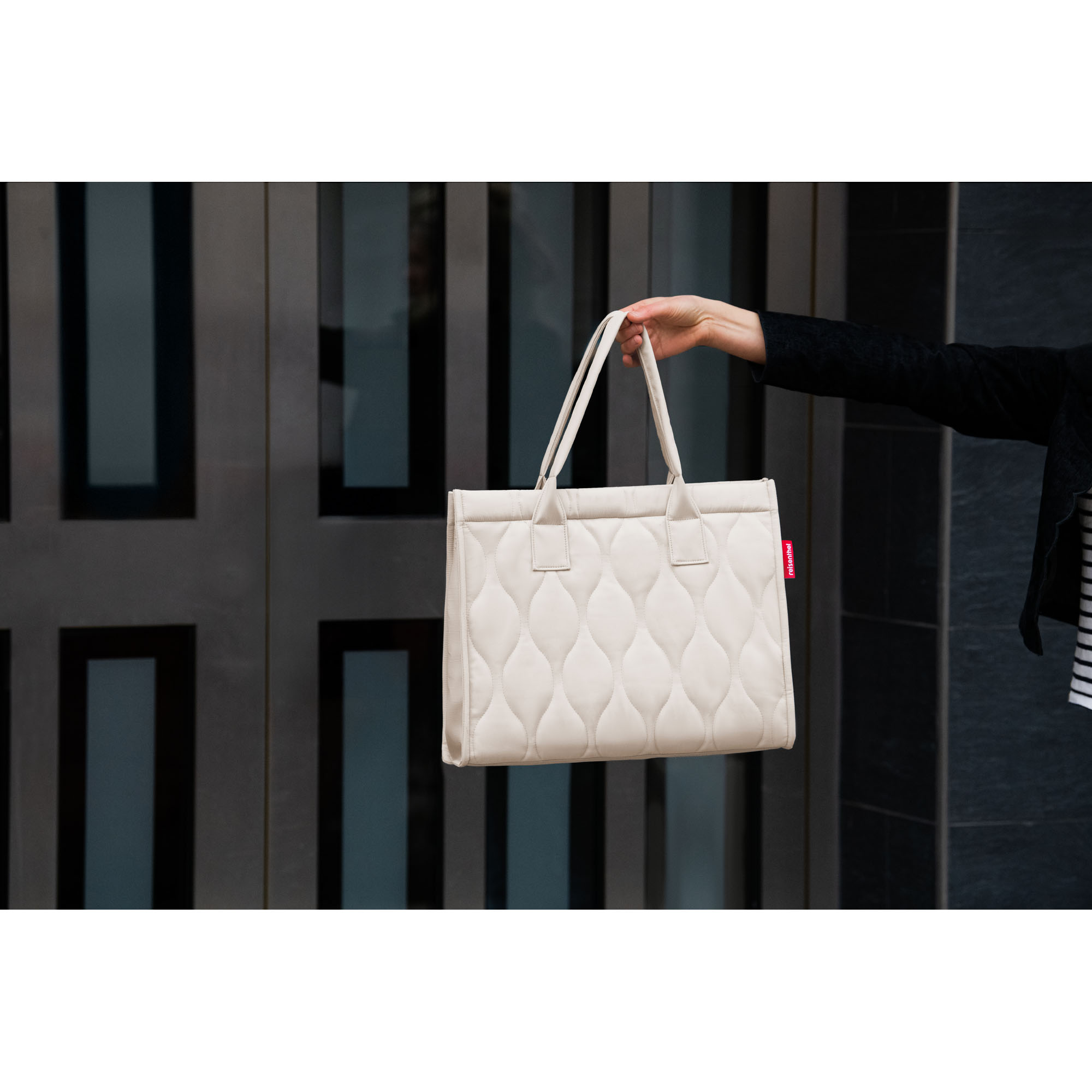 Shopper von Reisenthel, Modell Daily Shopper, in hellem Steinbeige mit Steppstruktur, von einer Person an den kurzen Griffen getragen