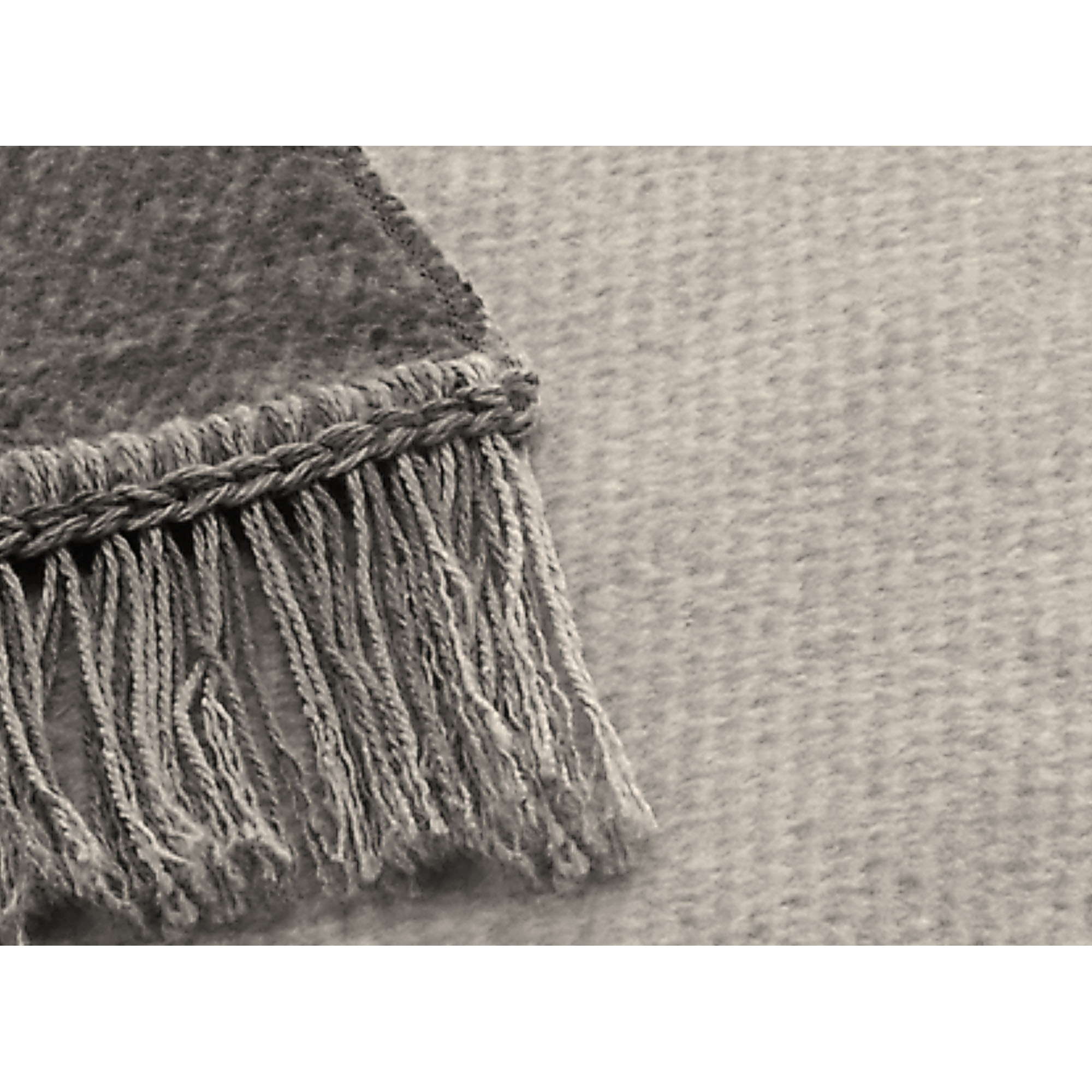 Nahaufnahme des Sofaschoners S&P silber mit grauem Gewebe, dunklerem Rand und langen Fransen.