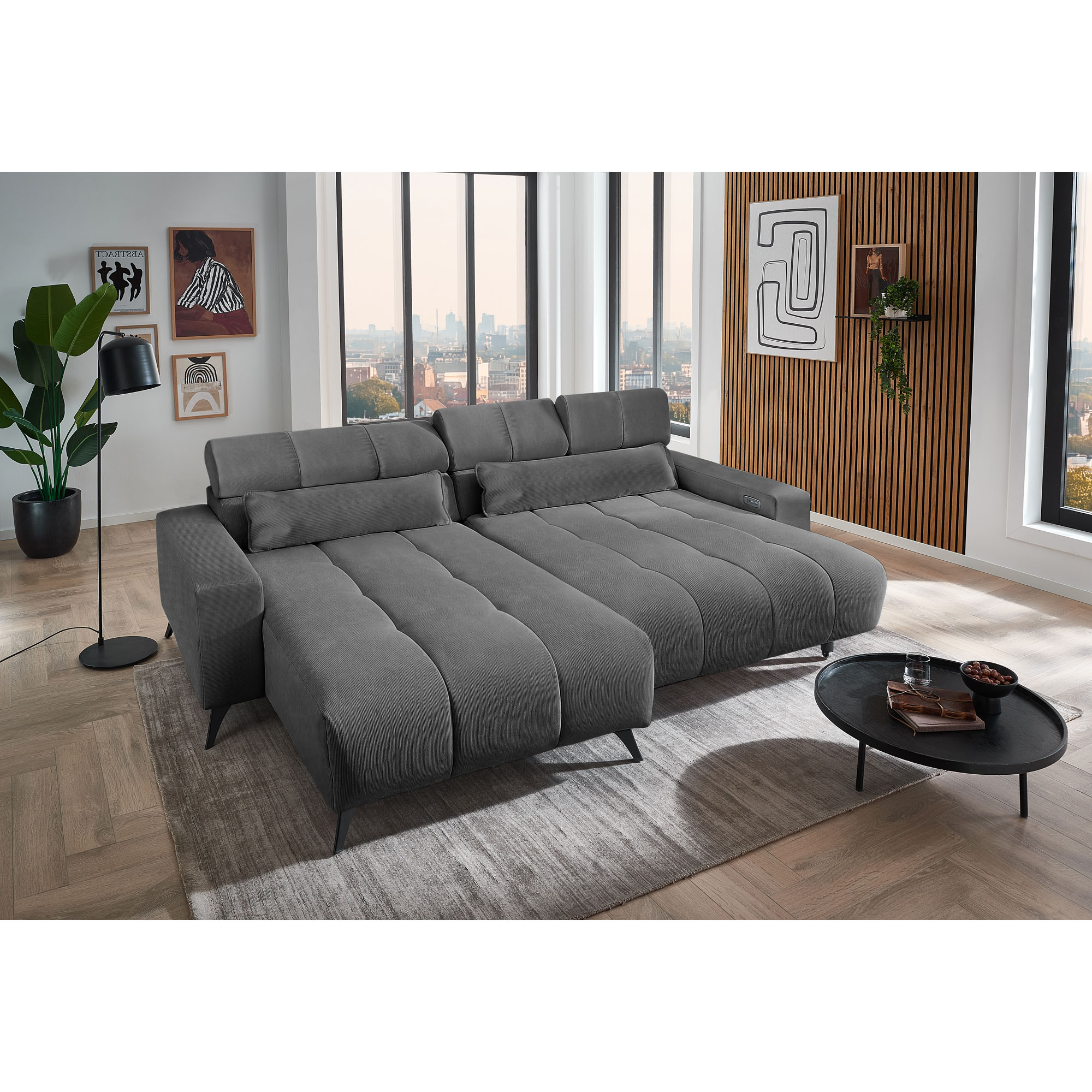 Dunkelgraues Ecksofa mit Ottomane links und ausgezogener Liegefläche in einem modernen Wohnzimmer mit Teppich und Couchtisch