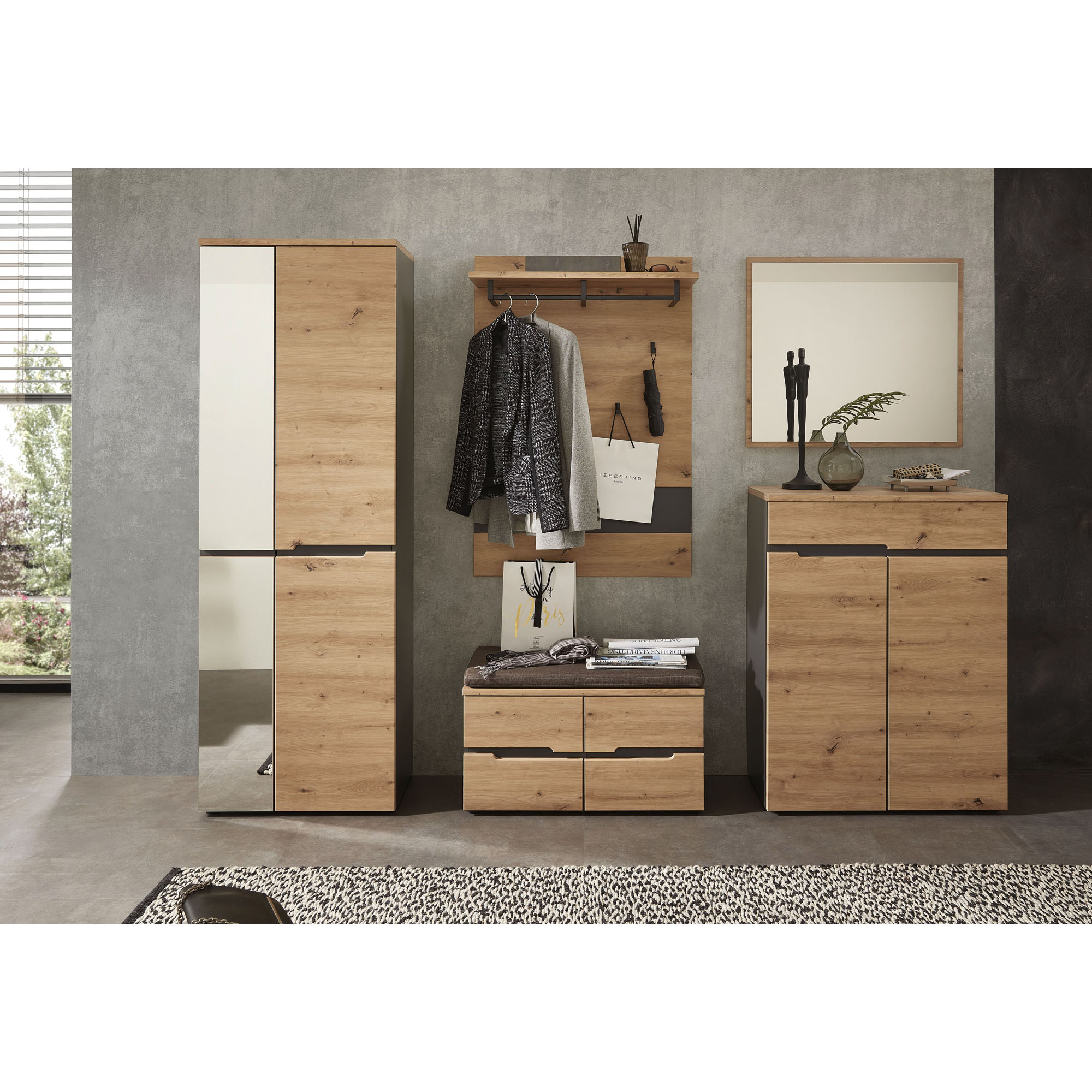 Eingestellter Eingangsbereich mit Wandpaneel in Holzoptik, Sitzbank, hohem Schrank und Kommode, ergänzt durch Kleidung und Accessoires.