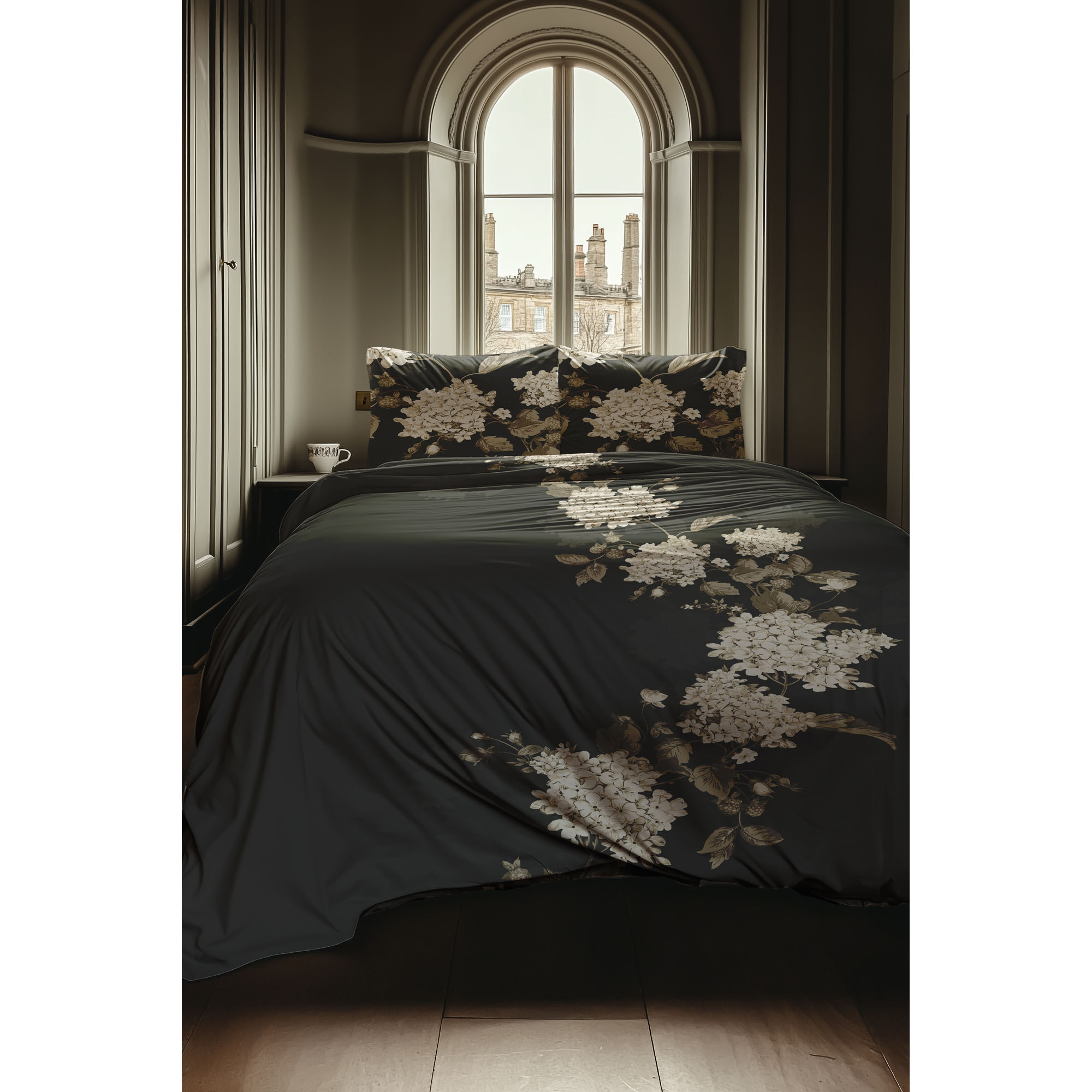 Bettwäsche Ivy in Classic Anthracite, 135 x 200 cm: bezogenes Bett in frontaler Schlafzimmerszene mit hellen Hortensienblüten auf anthrazitfarbenem Grund.