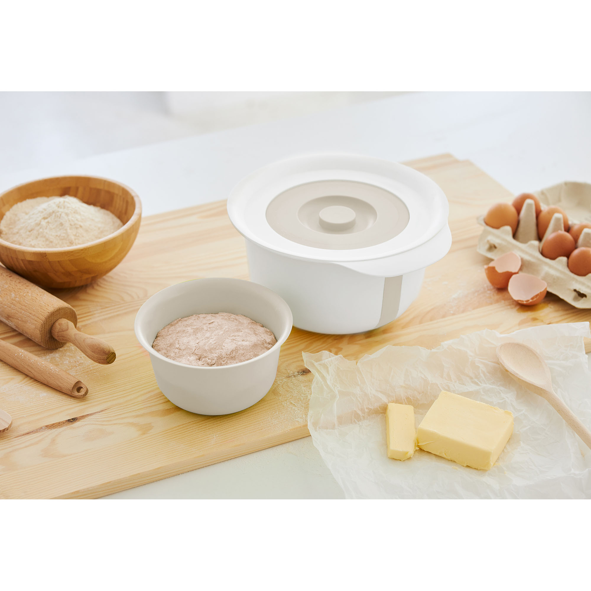Rührschüssel mit Deckel und Zubehör auf einer Küchenarbeitsplatte neben Backzutaten