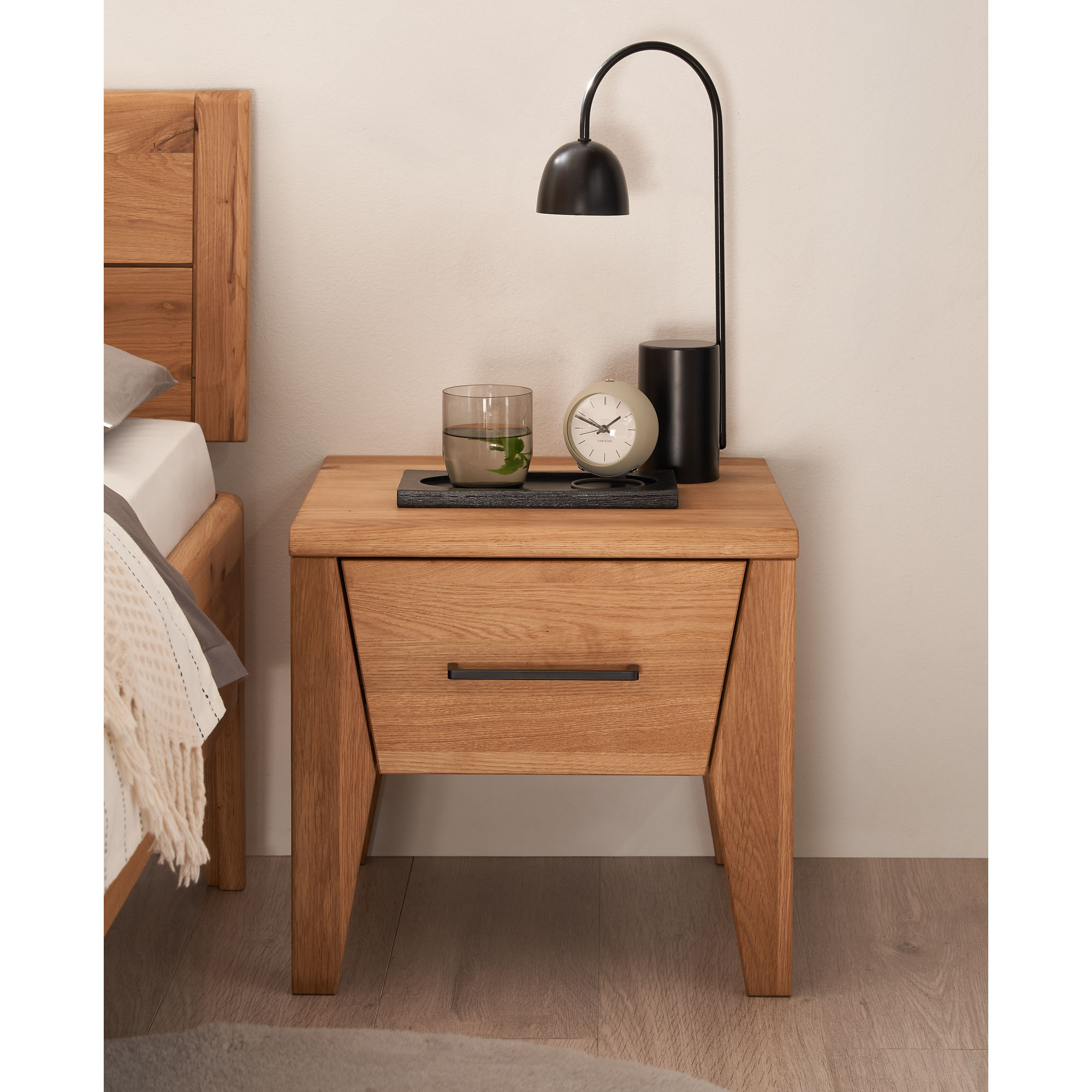 Nachttisch aus Holz mit einer Schublade neben einem Bett im Schlafzimmer