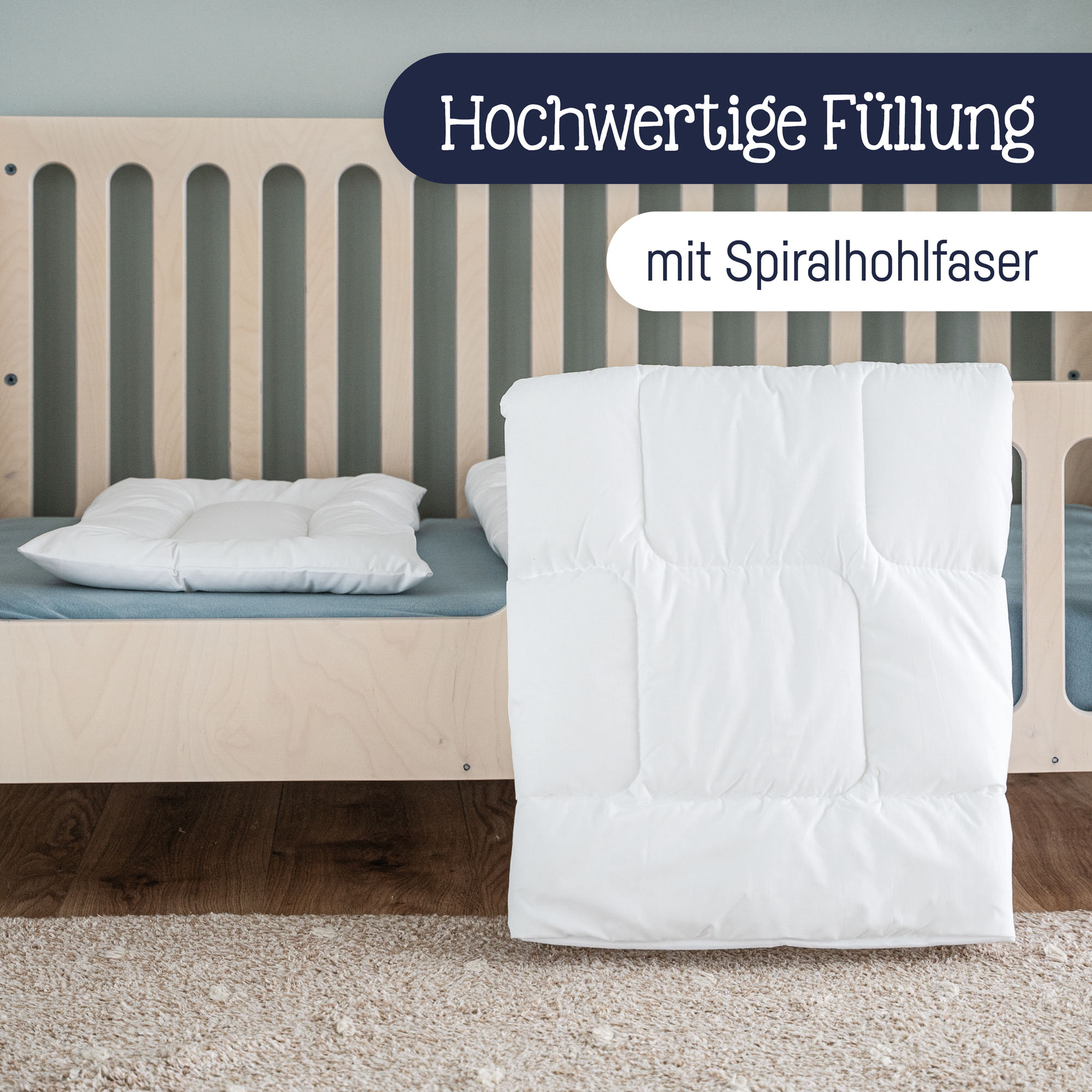 Weiße Steppdecke steht vor einem Kinderbett, Kissen liegt auf der Matratze