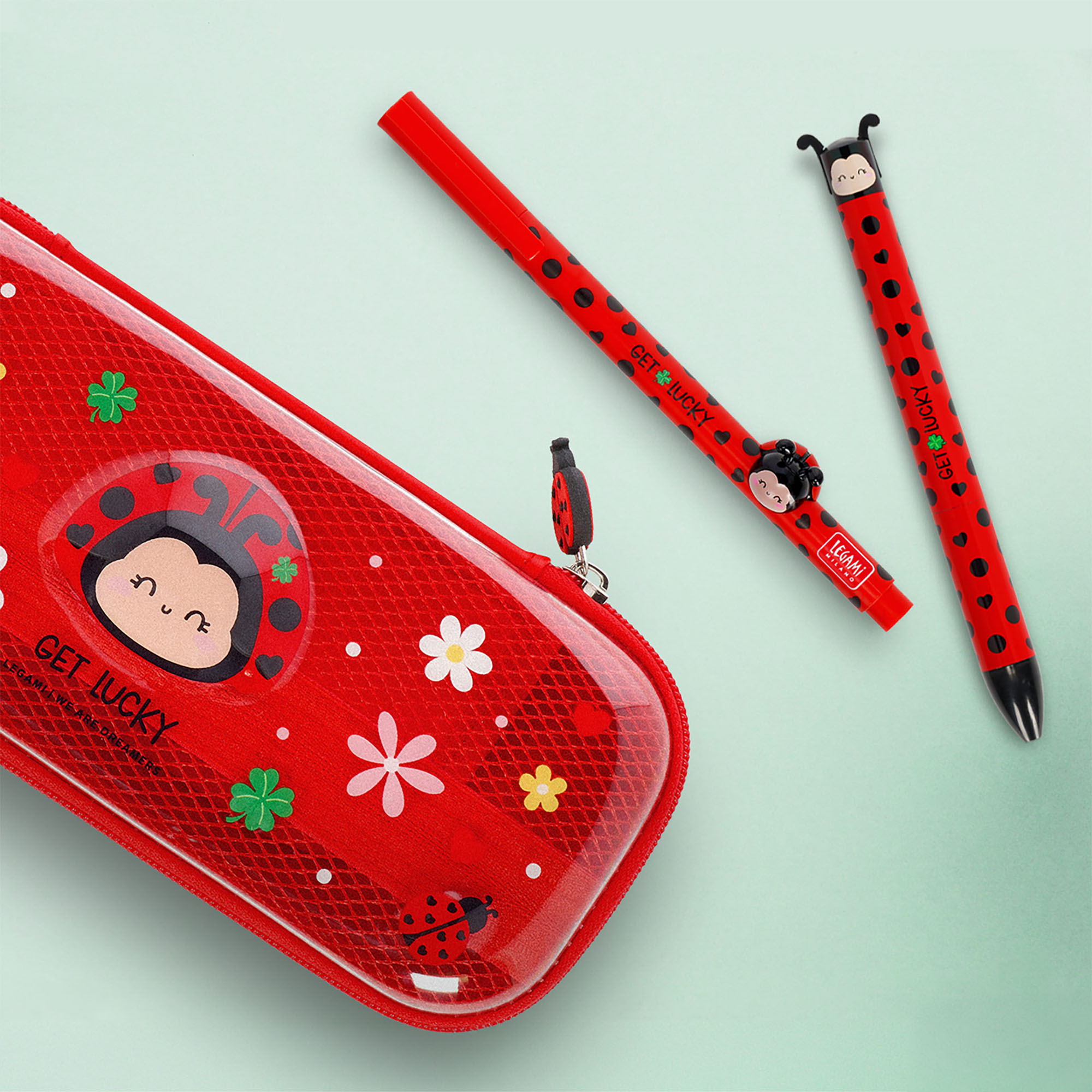 Roter Gelstift mit Marienkäfer-Aufsatz, neben einem roten Marienkäfer-Federmäppchen und dem Zweifarben-Kugelschreiber der Serie dargestellt.