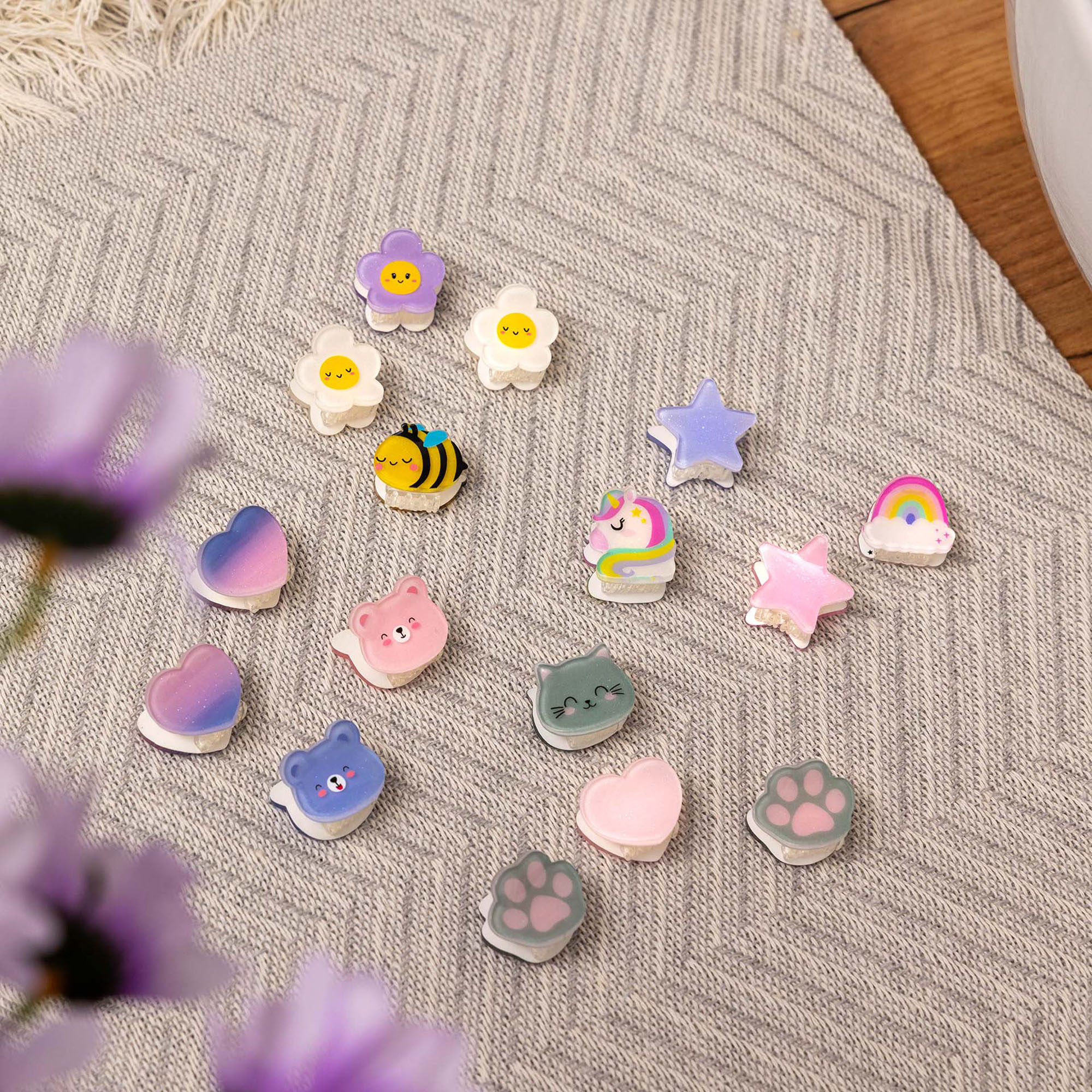 Haarspangen-Set, 4 Stück – Biene von Legami: Verschiedene kleine Haarspangen auf einem gestrickten Stoff.