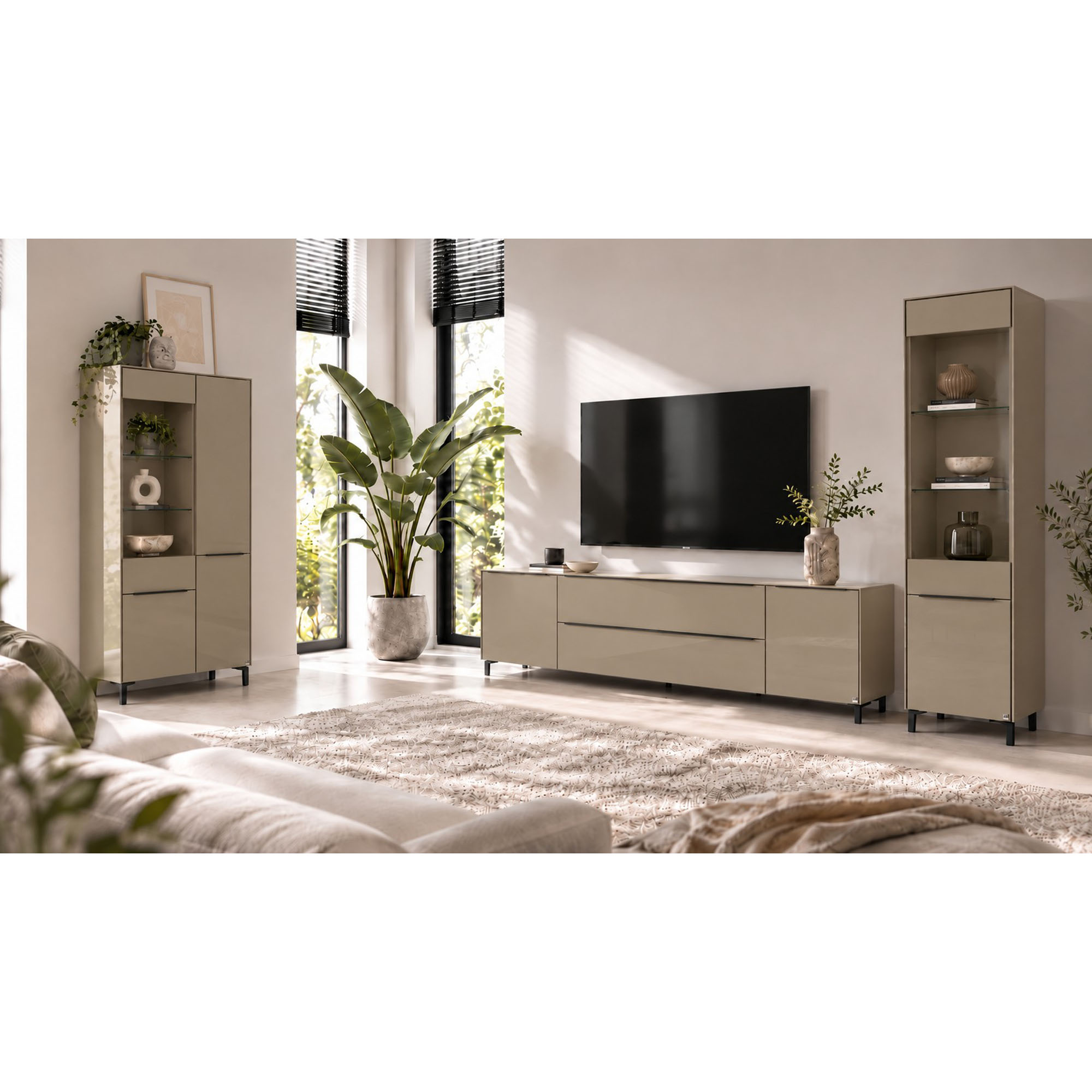 Helles Wohnzimmer mit einem taupefarbenen Lowboard auf dunklen Füßen unter einem wandmontierten Fernseher. Links und rechts stehen passende Vitrinenschränke mit offenen Glasfächern. Das Lowboard ist mit einem erhöhten Fußgestell dargestellt.