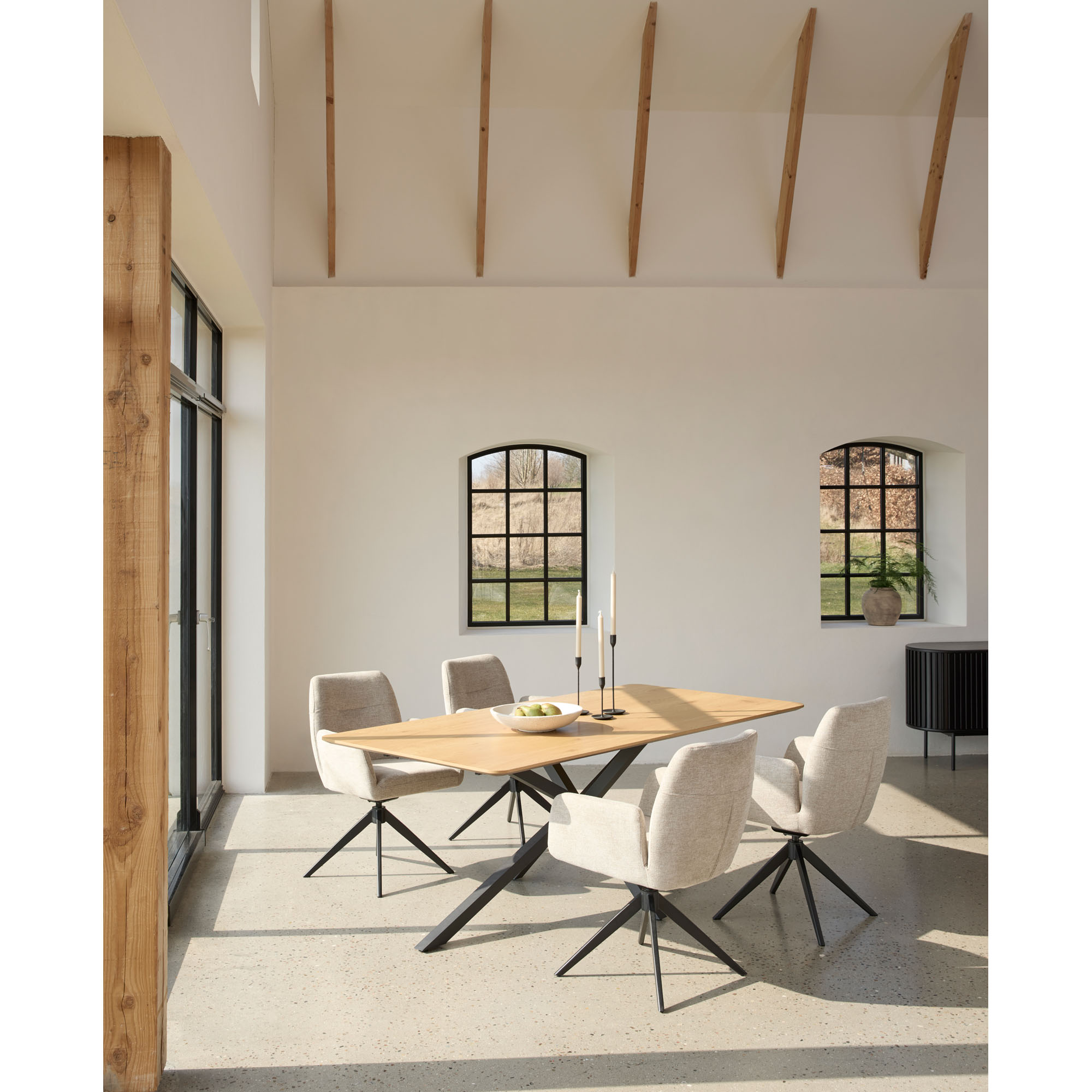 Moderner Essbereich mit rechteckigem Holztisch und schwarzem Kreuzgestell, kombiniert mit vier schwarzen Polsterstühlen auf hellem Teppich.