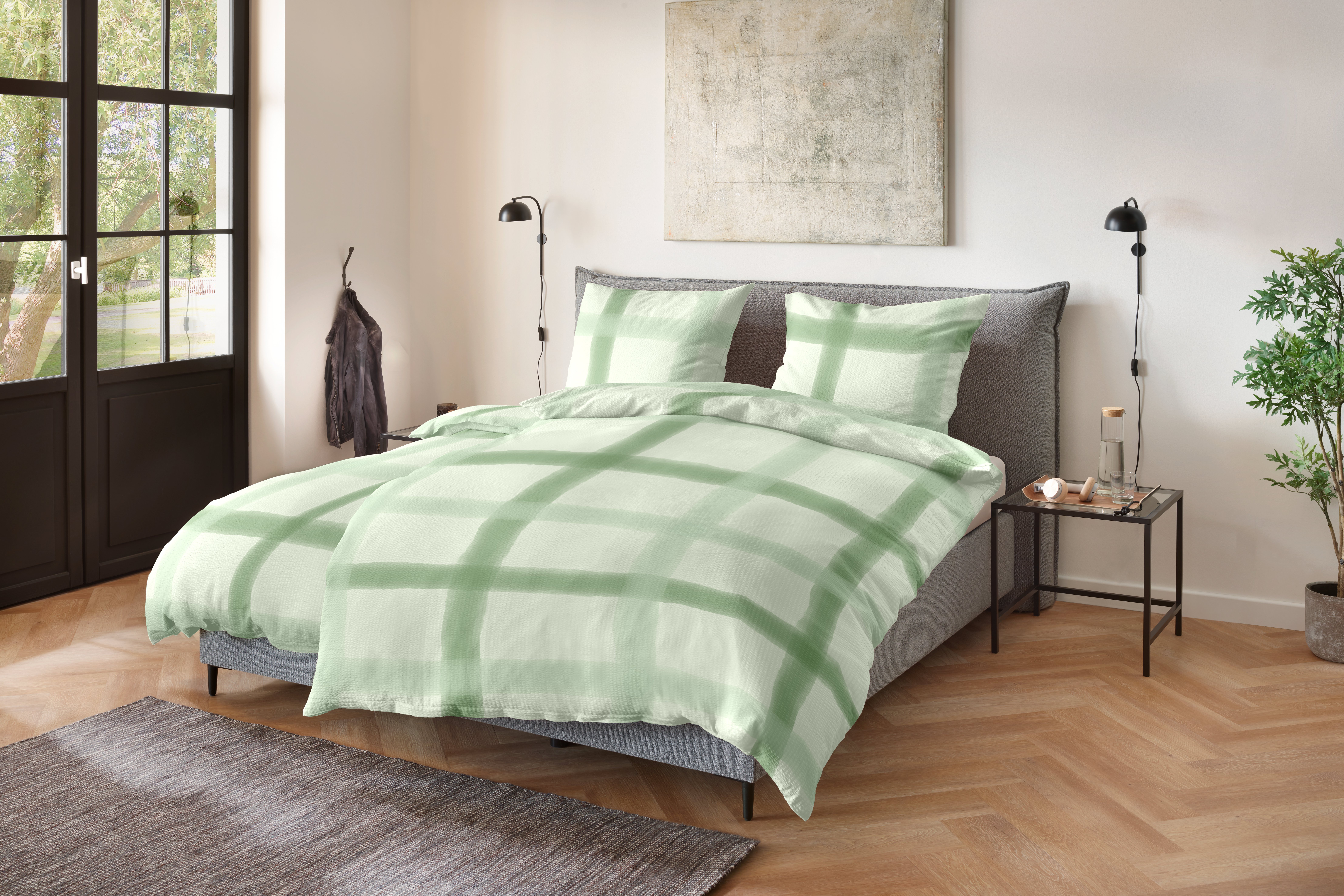 Doppelbett mit grün-weißer Bettwäsche im großflächigen Karomuster; Größe 135 x 200 cm.