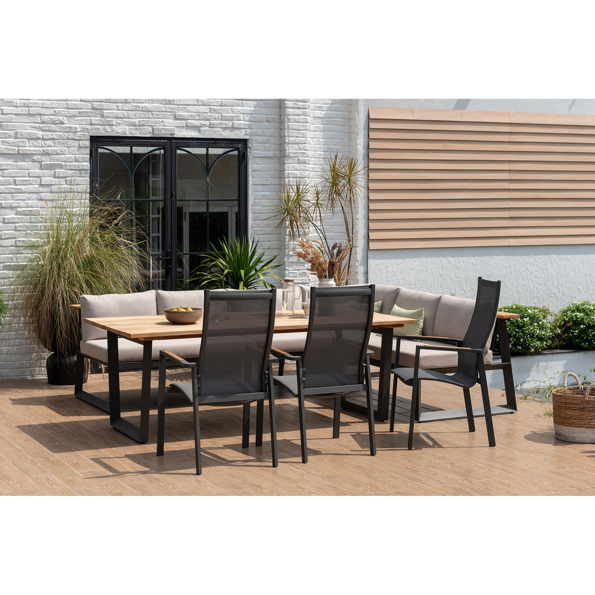 Gartenessgruppe mit rechteckigem Tisch, mehreren Gartenstühlen und gepolsterter Eckbank auf einer Terrasse