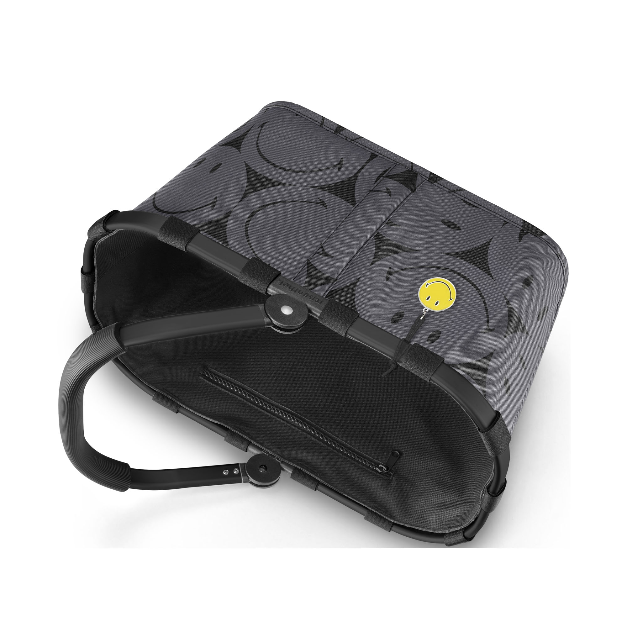Einkaufskorb von Reisenthel, Modell Carrybag, in Grau mit großflächigem Smiley-Muster, auf die Seite gelegt mit sichtbarem Rahmen und eingeklapptem Griff.