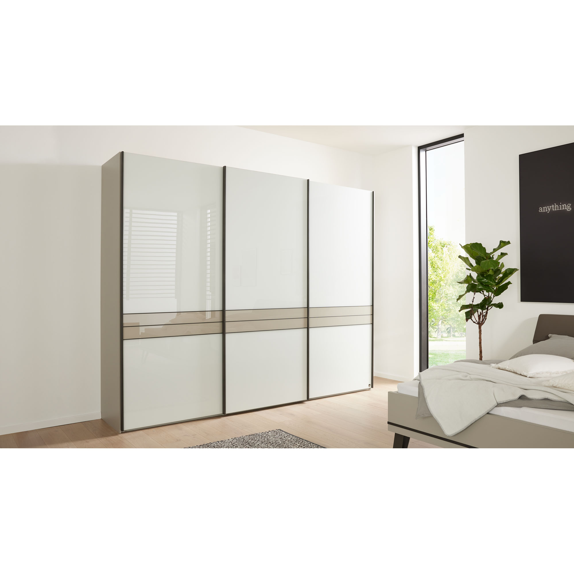 Kleiderschrank Interliving 1032 mit Schiebetüren im Schlafzimmer platziert, neben Bett und Fenster in moderner Raumgestaltung