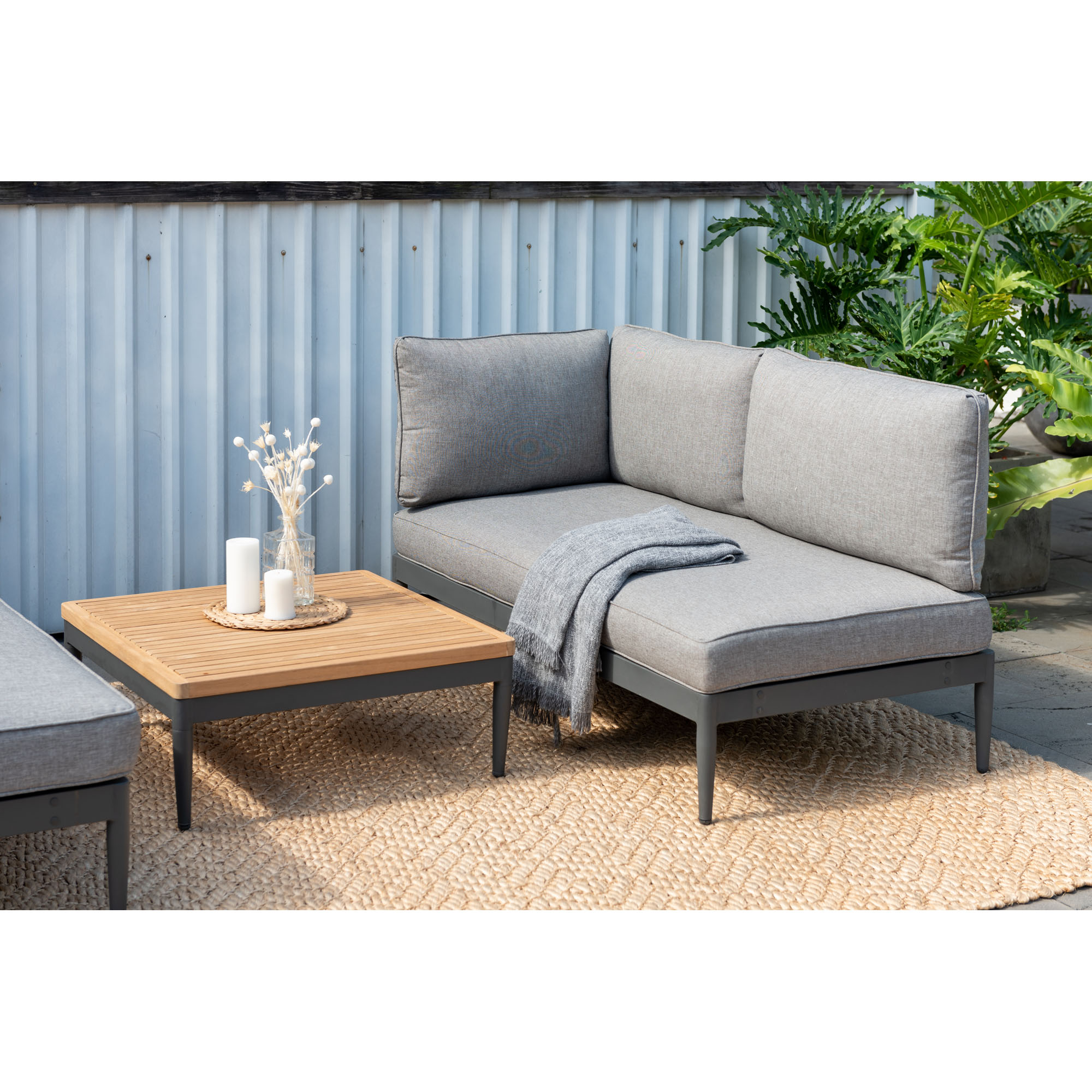 Garten Loungeecke mit Ecksofa, Tisch und Dekoration auf einer Terrasse mit Teppich