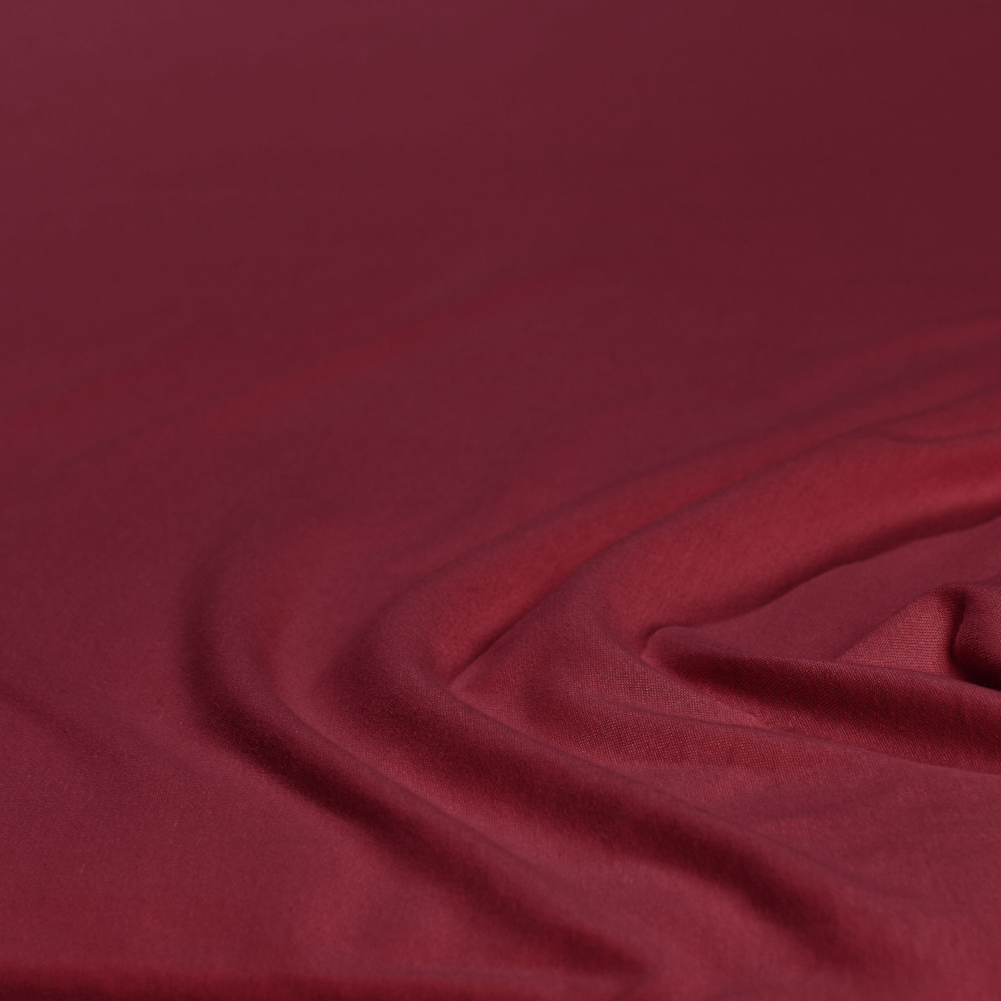 Nahaufnahme des Stoffes in Bordeaux mit leichten Falten; Farbe und Oberflächenstruktur des Produkts sind erkennbar; Größe 100 x 200 x 30 cm.