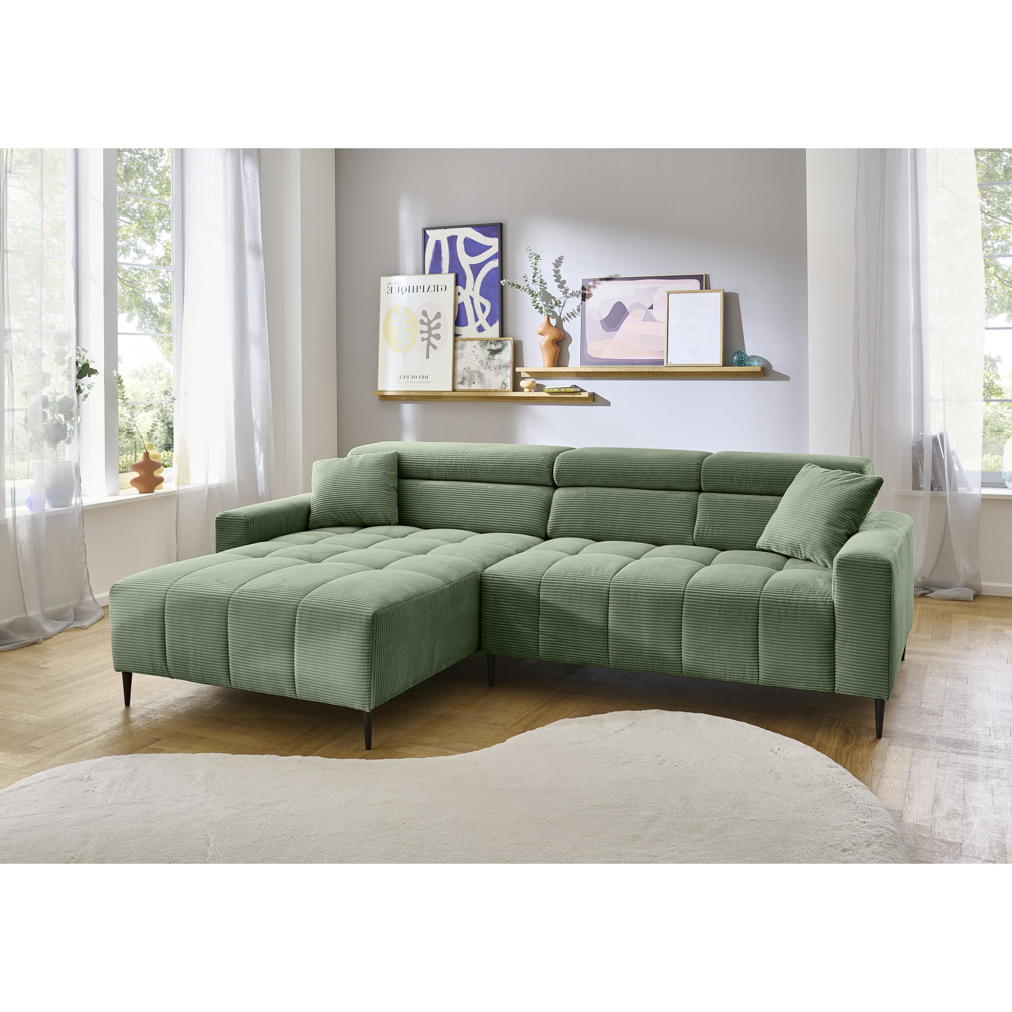 Modernes Wohnzimmer mit Ecksofa in grünem Cordstoff, heller Raum mit natürlichem Licht und dekorativer Wandgestaltung.