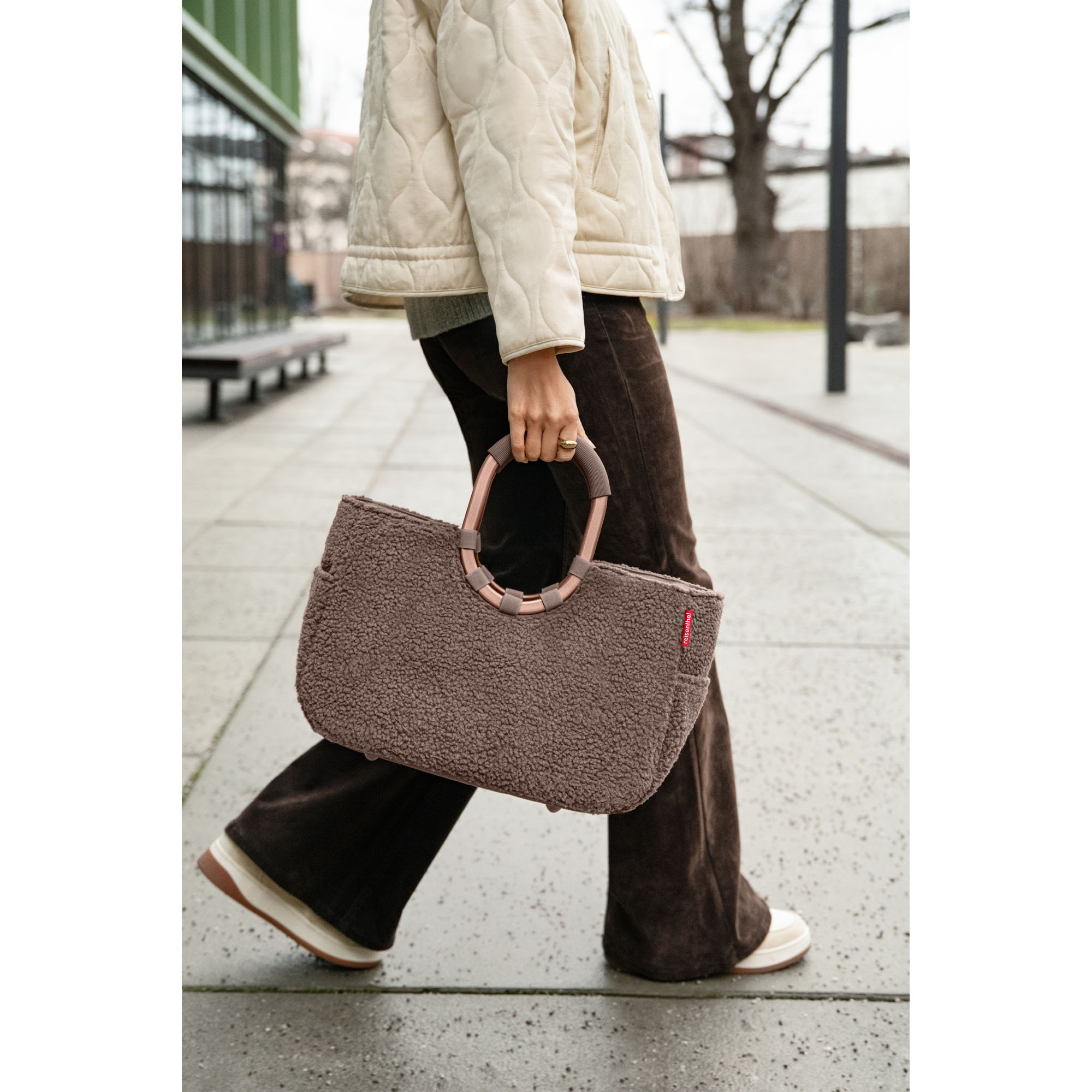 Shopper mit Ringgriffen von Reisenthel, Modell Loopshopper M, in Schokoladenbraun aus Teddyfleece, von einer Person an den ovalen Ringgriffen getragen