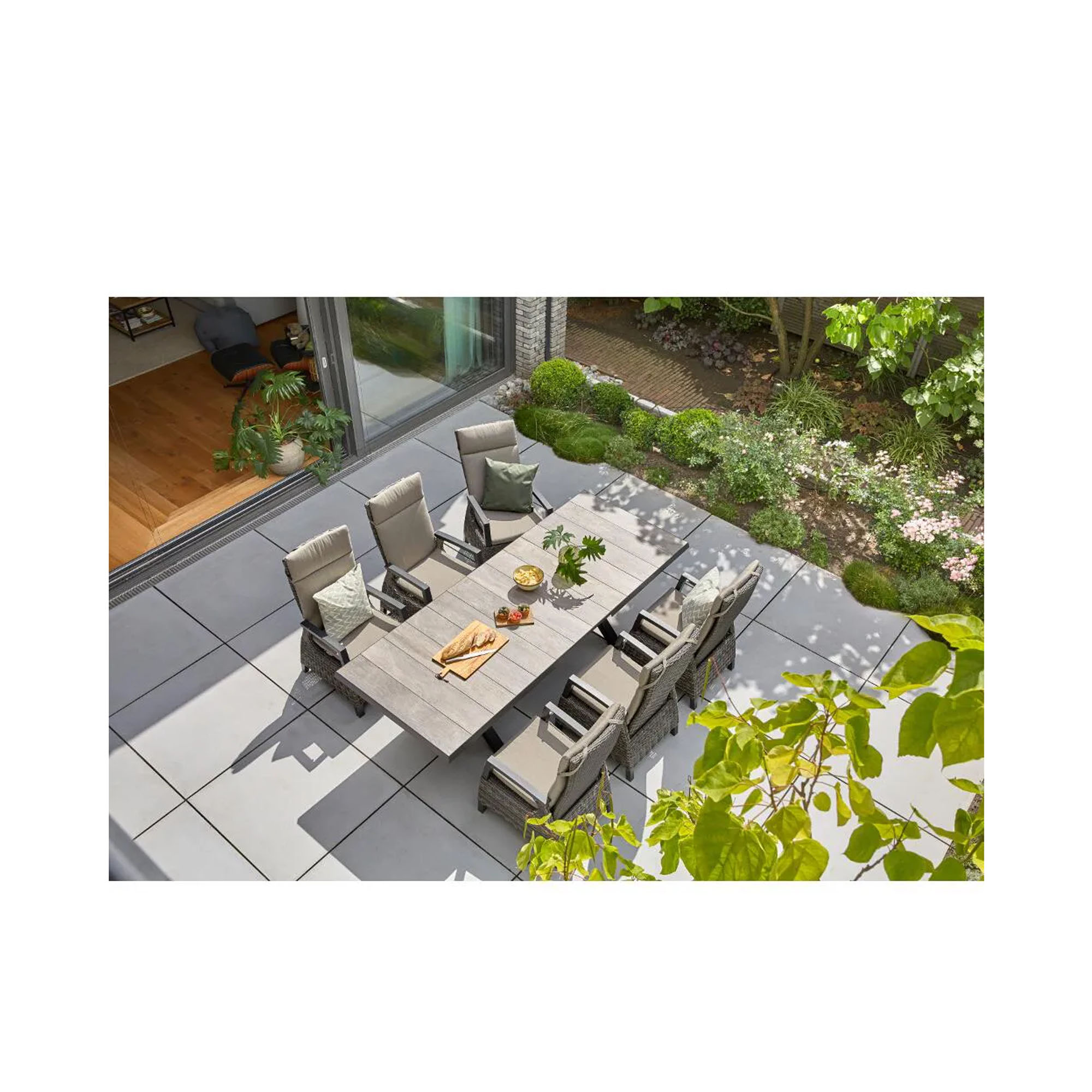 Großzügige Terrasse mit Esstisch und mehreren grauen Hochlehner-Gartenstühlen aus Polyrattan im Ensemble.