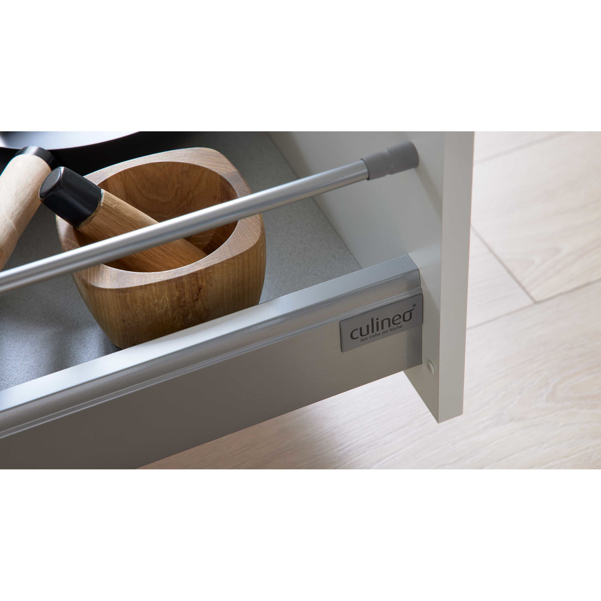 Detailaufnahme einer geöffneten Küchenschublade mit sichtbarem Markenlogo und Holzstößel