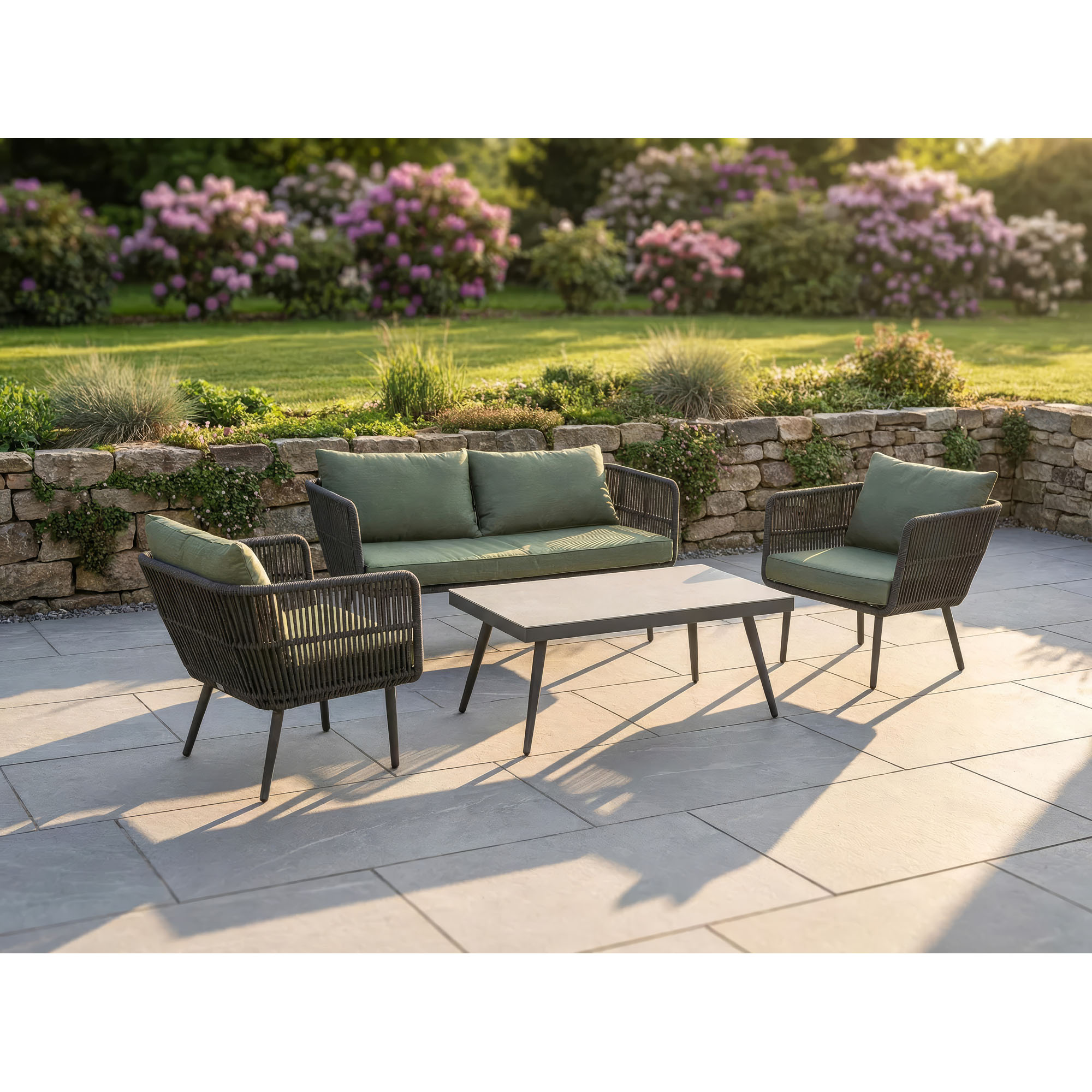 Gartenlounge mit Sofa Sesseln und Tisch auf einer Terrasse im Garten mit Bepflanzung im Hintergrund