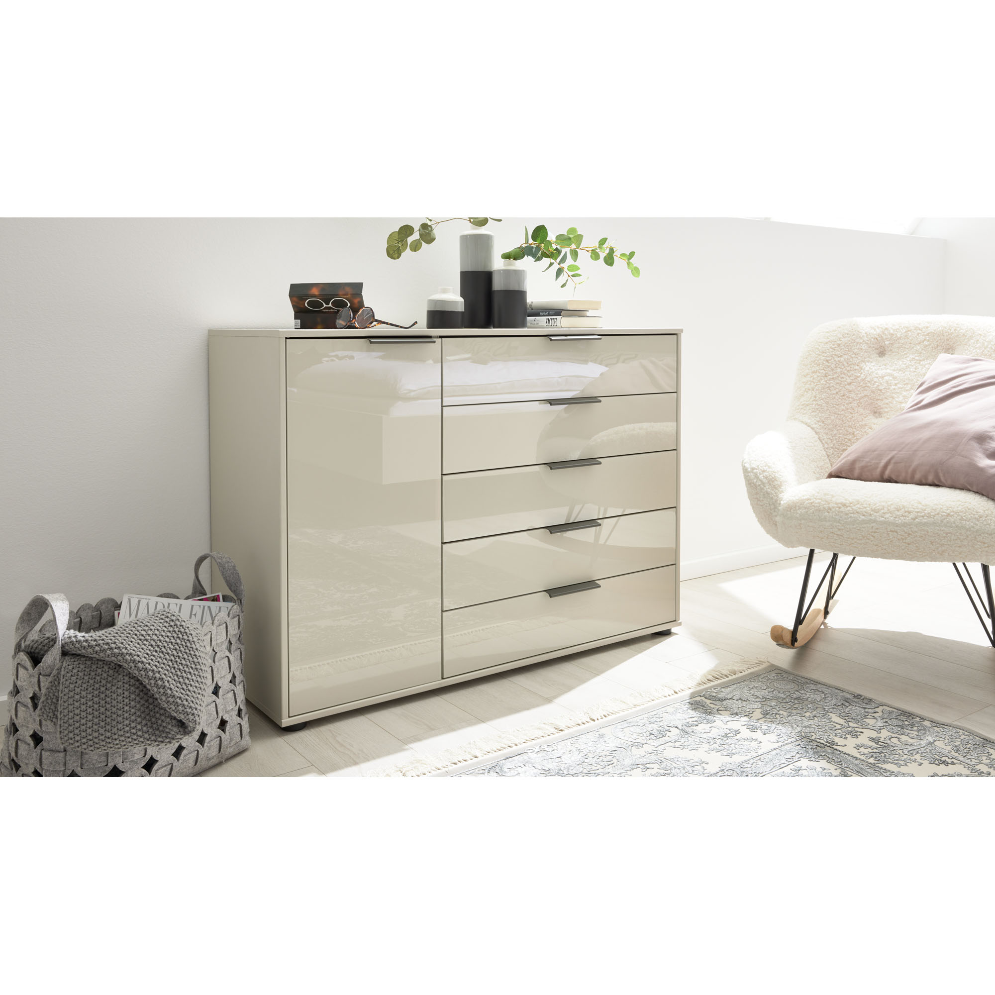 Helle Kommode Interliving 1026 mit Hochglanzfronten und Griffen, dekoriert mit Vasen und Büchern in einem modern eingerichteten Raum