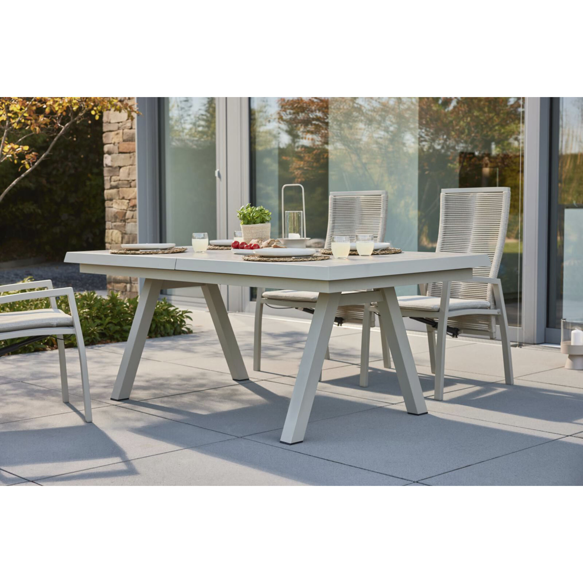 Gartentisch mit mehreren Gartenstühlen auf einer Terrasse vor einem Wohnhaus