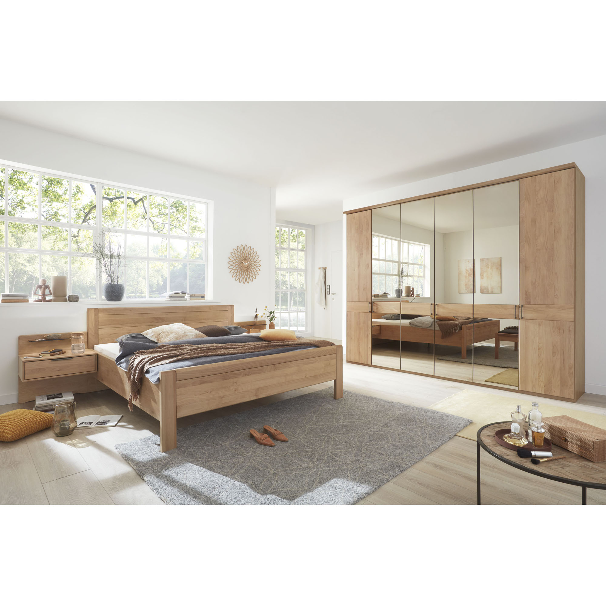 Helles Schlafzimmer mit Doppelbett und großem Kleiderschrank in Holzoptik mit teilweise verspiegelten Türen und Querblende in Holzoptik