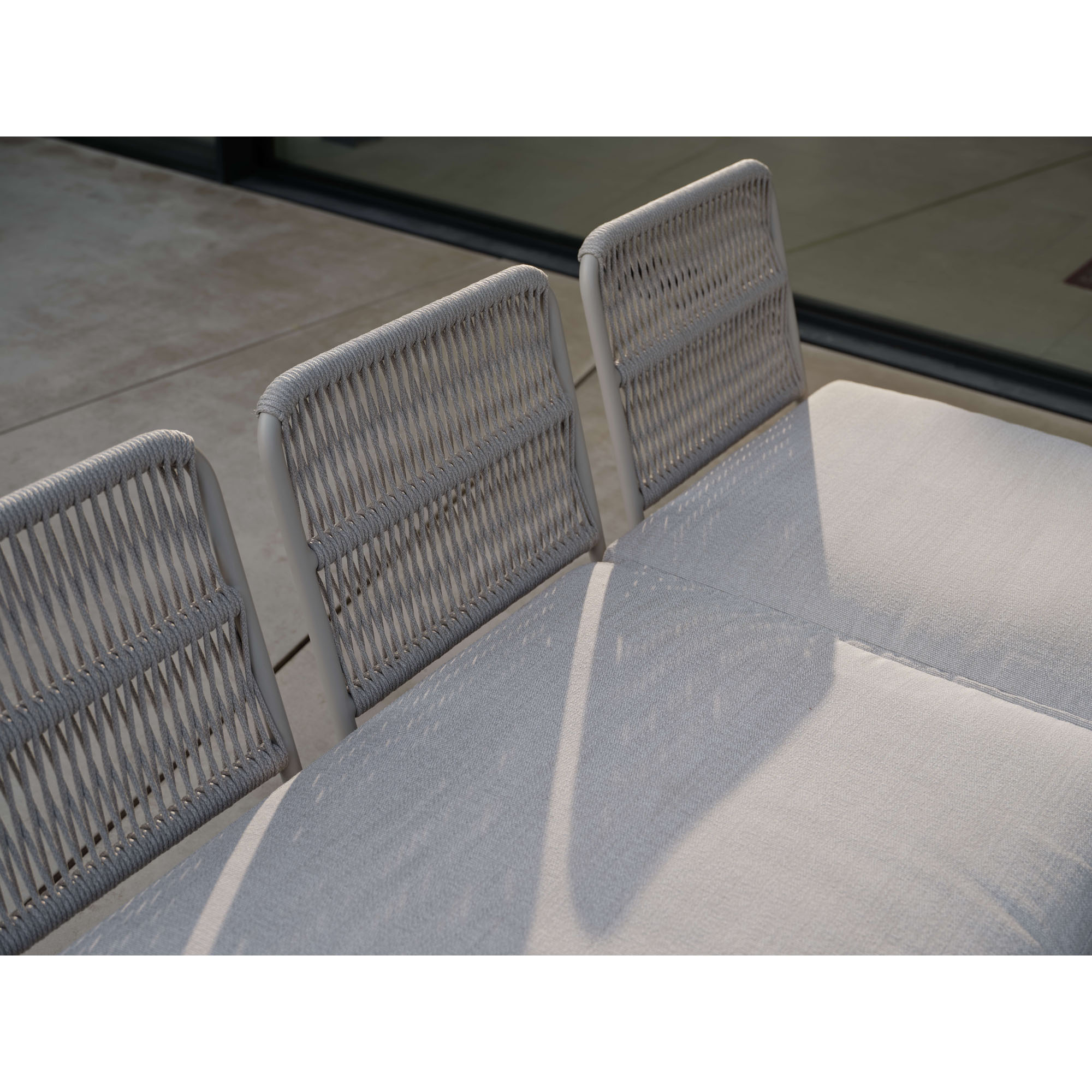 Detailaufnahme der oberen Rückenlehne eines Outdoor Sofas mit geflochtener Struktur und Sitzpolster im Vordergrund.