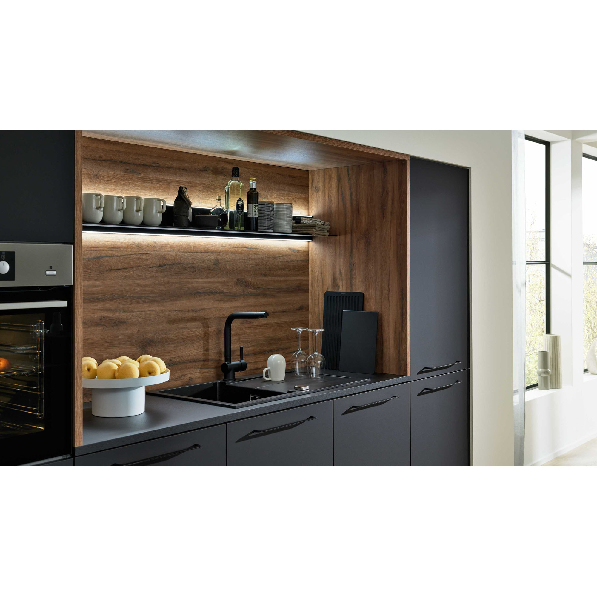 Detailaufnahme der Küchenzeile mit dunkler Spüle, Holzrückwand, beleuchtetem Regal und Küchengeräten
